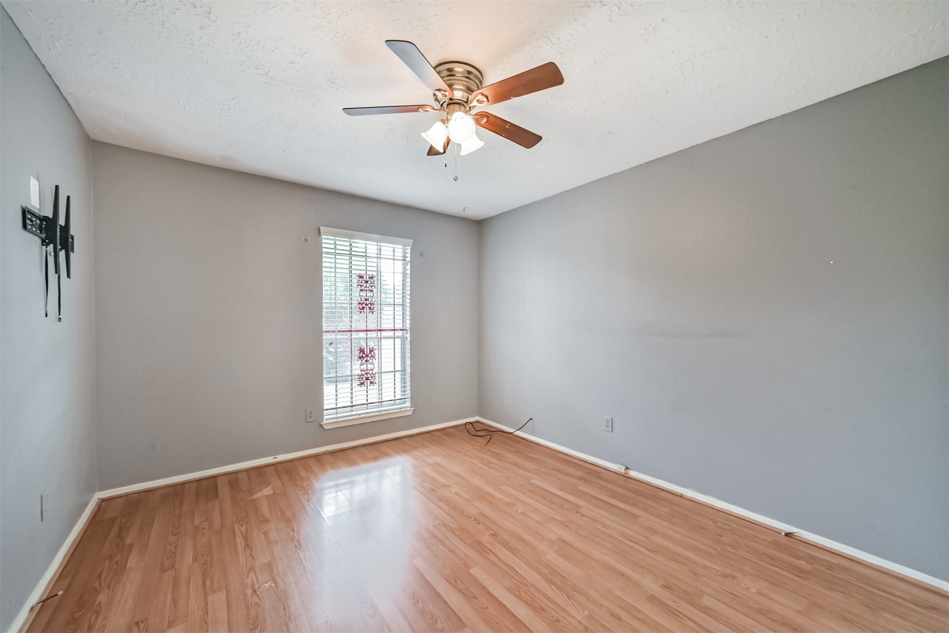 16510 Quiet Quail Drive, Houston, TX 77489 Bright room with hardwood floors, neutral gray walls, and a ceiling fan, perfect for a cozy retreat or home office.