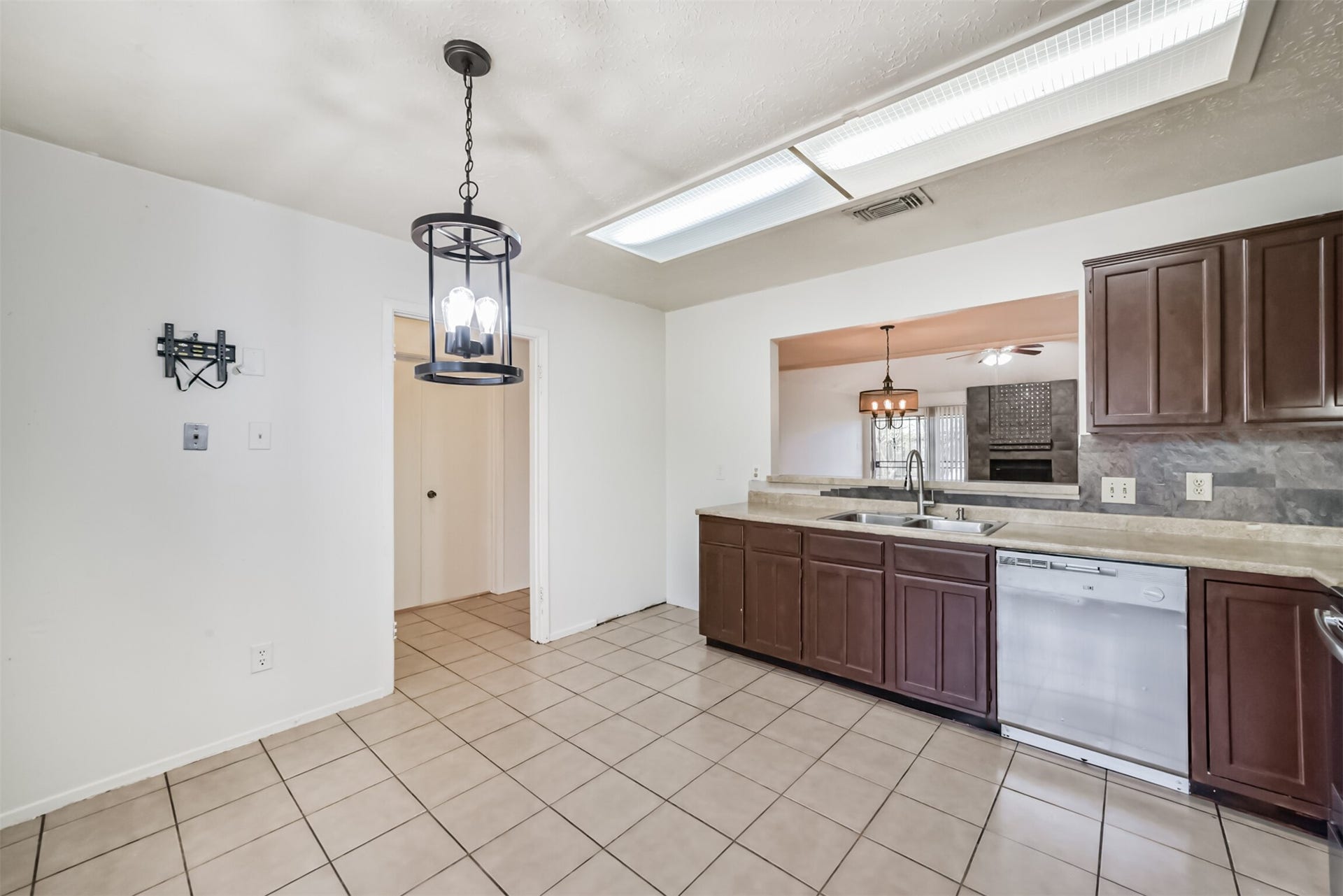 16510 Quiet Quail Drive, Houston, TX 77489 Spacious kitchen featuring dark wood cabinetry, modern light fixtures, and a convenient pass-through window to the living area.