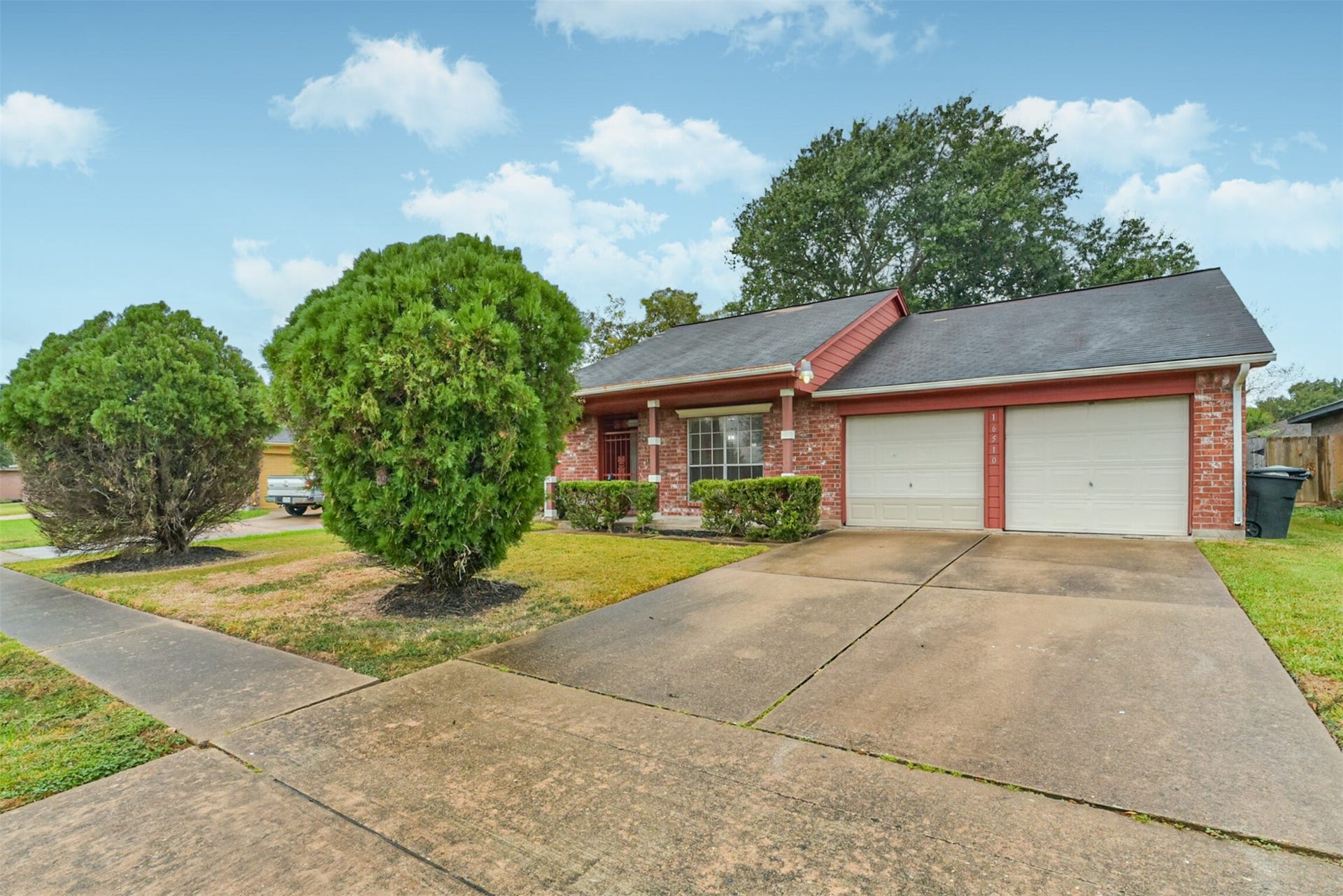 16510 Quiet Quail Drive, Houston, TX 77489 Charming brick home with a welcoming porch, dual garage doors, and a spacious driveway. Lush greenery and a well-maintained lawn enhance its curb appeal.