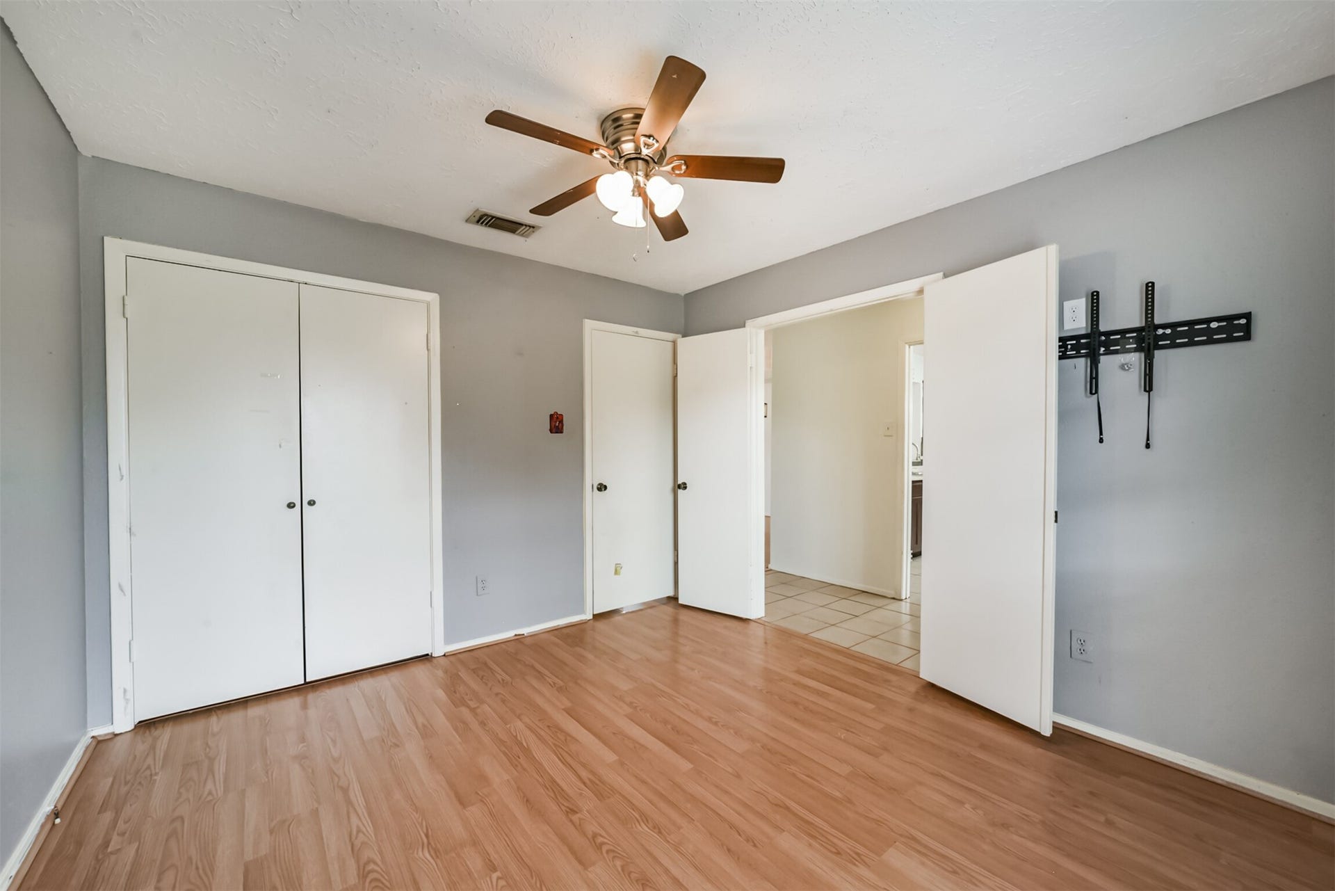 16510 Quiet Quail Drive, Houston, TX 77489 Spacious bedroom featuring laminate wood flooring, a ceiling fan, and ample closet space with dual white doors, offering a bright and airy feel.