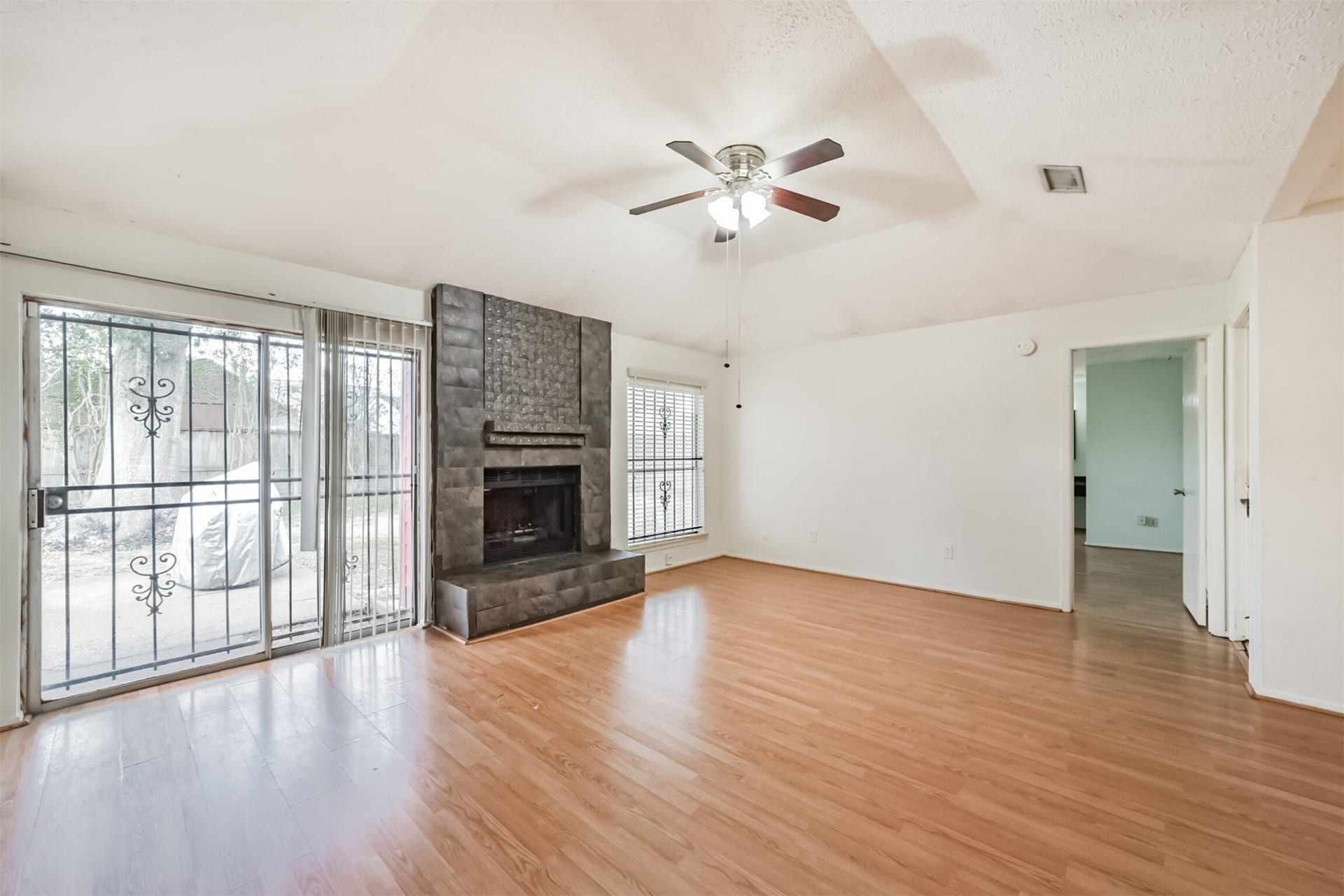16510 Quiet Quail Drive, Houston, TX 77489 Spacious living room featuring laminate wood flooring, a cozy fireplace, and abundant natural light from large windows and sliding glass doors leading to the patio.