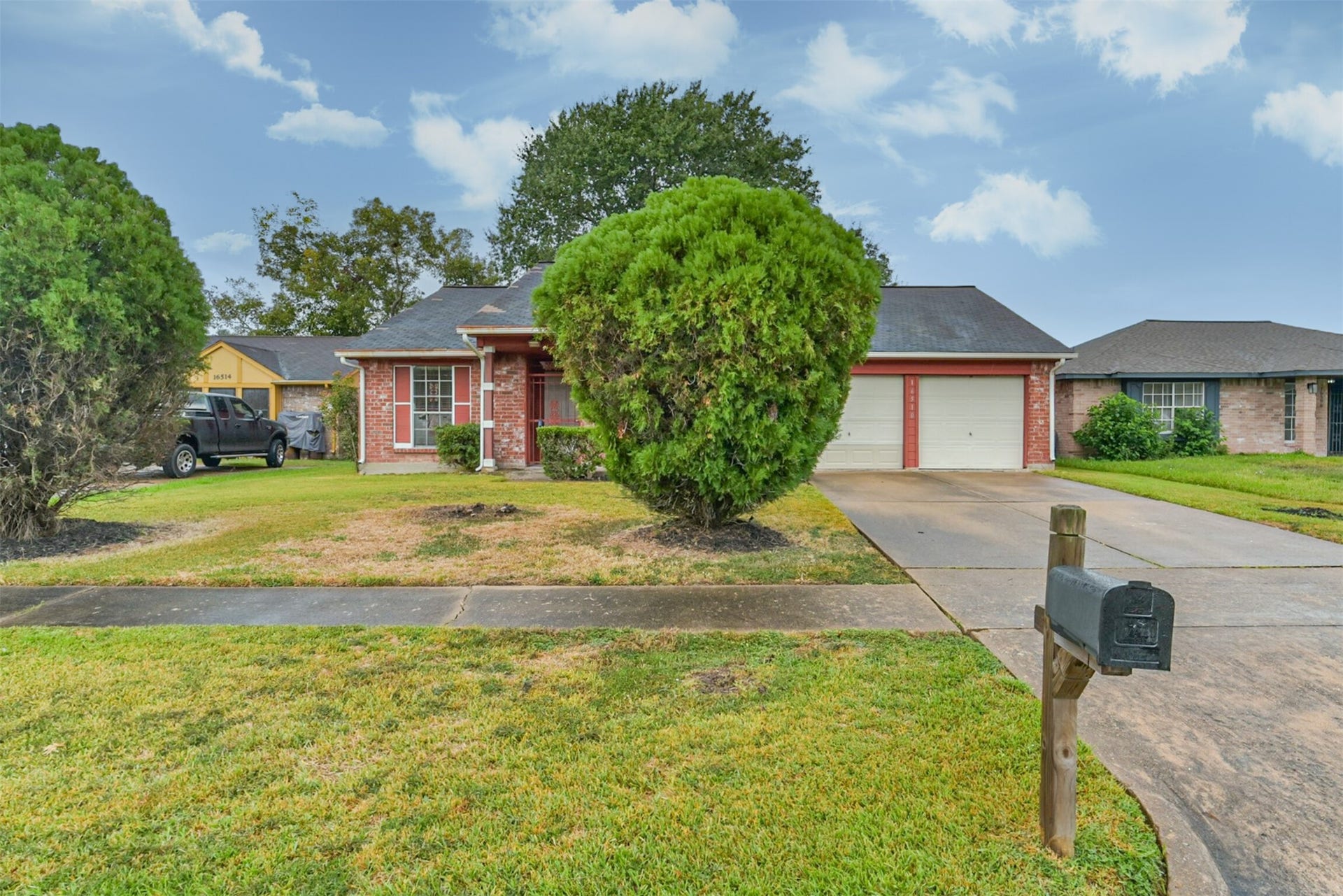 16510 Quiet Quail Drive, Houston, TX 77489 One story brick home with a welcoming front porch, two-car garage, and lush greenery.
