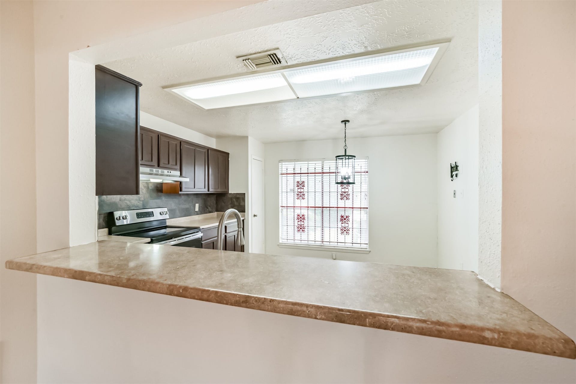 16510 Quiet Quail Drive, Houston, TX 77489 Bright kitchen with dark cabinetry, modern appliances, and a cozy dining nook featuring a unique stained glass window.