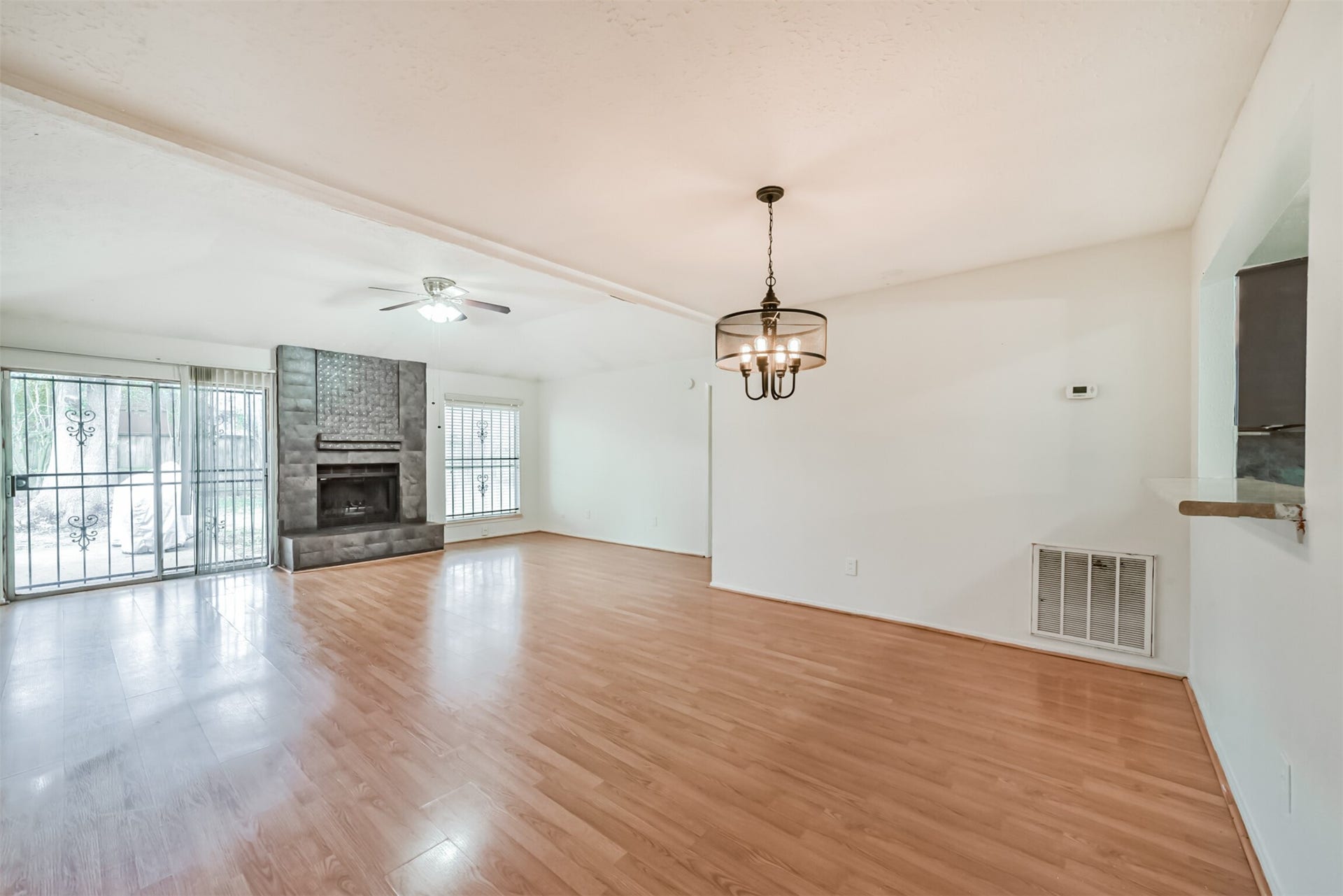 16510 Quiet Quail Drive, Houston, TX 77489 Spacious living area with elegant hardwood floors, a cozy fireplace, and abundant natural light from large windows and a sliding door.
