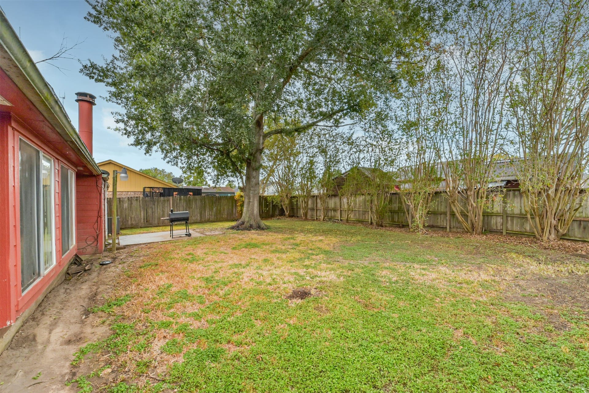 16510 Quiet Quail Drive, Houston, TX 77489 Expansive backyard with lush greenery, mature trees, and a cozy patio perfect for outdoor grilling and relaxation.