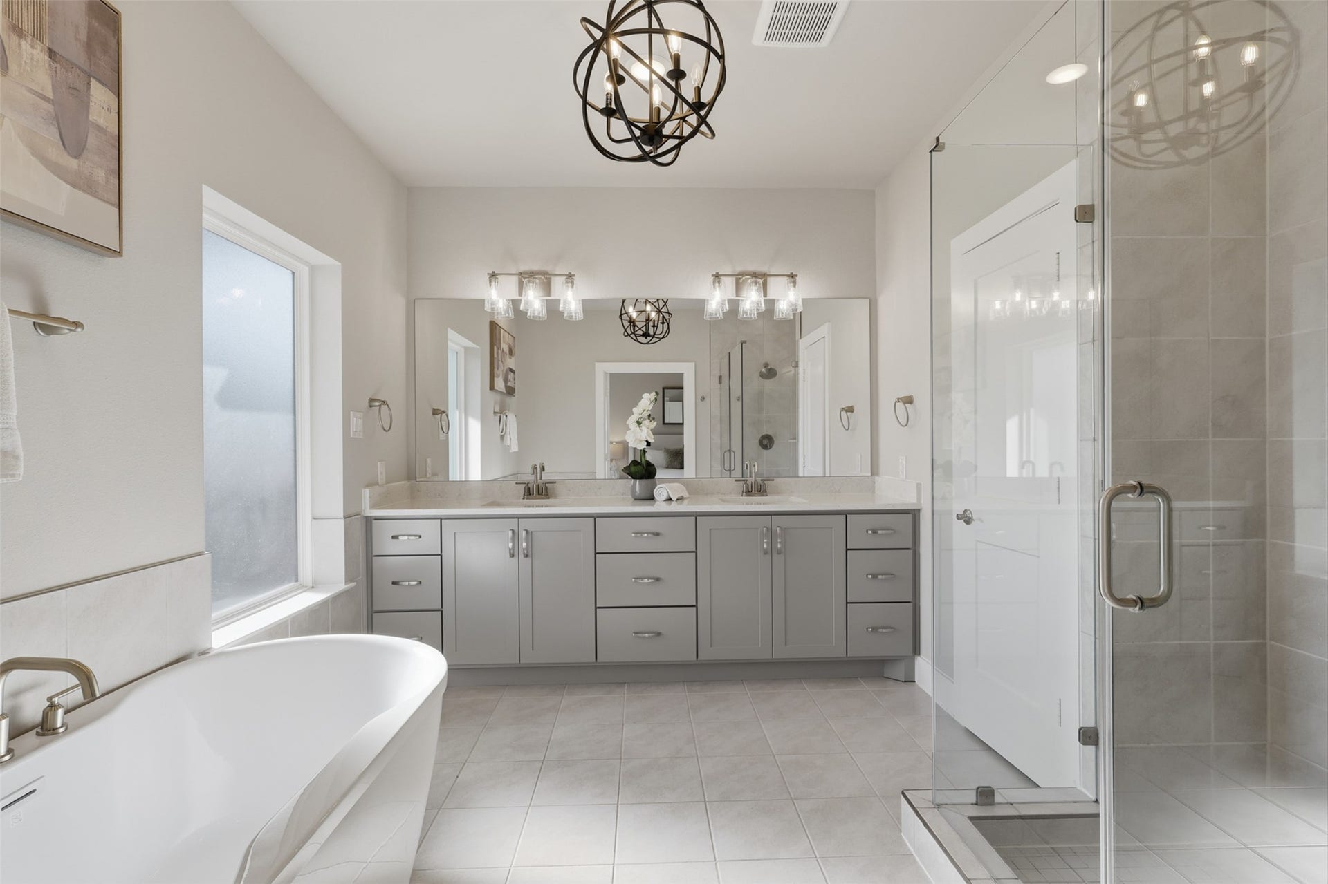 1444 W 34th 1/2 Street, Houston, TX 77018 The spa-inspired primary bath features a long dual-sink vanity, oversized mirror, frameless glass shower, and a freestanding soaking tub.