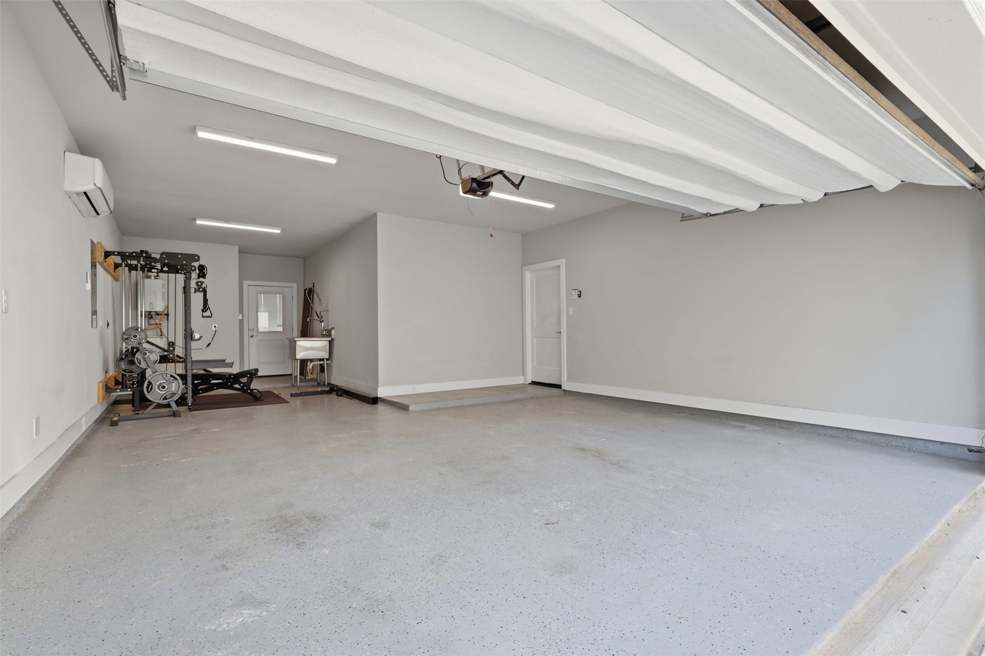 1444 W 34th 1/2 Street, Houston, TX 77018 The upgraded three-car tandem garage is a standout feature with epoxy-coated floors, insulated garage doors, an industrial utility sink, and a dedicated split-system A/C - perfect for a home gym, workshop, or climate-controlled flex space.