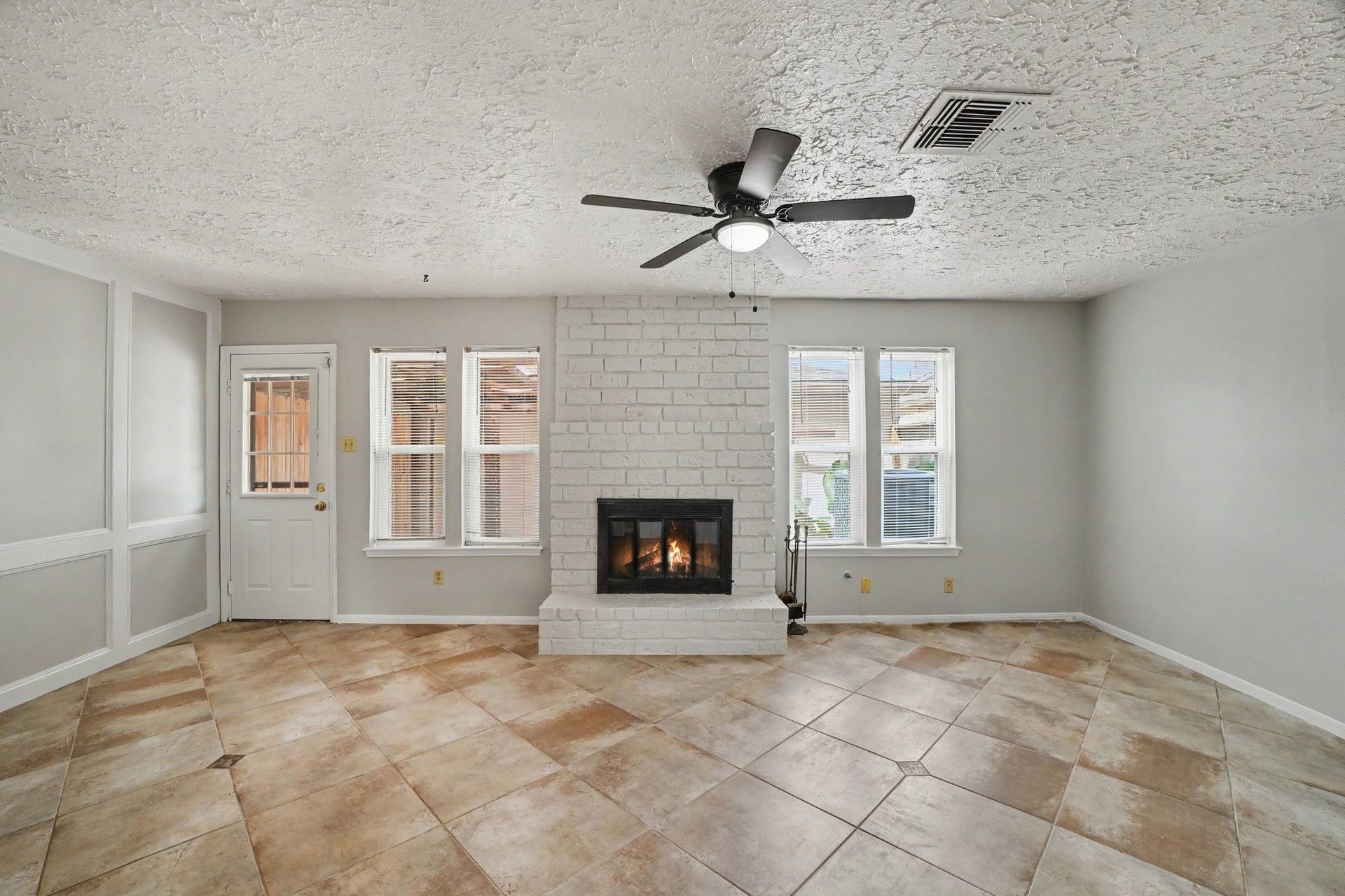 44 Chapparal Court, Missouri City, TX 77459 This spacious living area offers a warm and open feel, highlighted by a cozy painted brick fireplace with a extended hearth that serves as an inviting centerpiece.