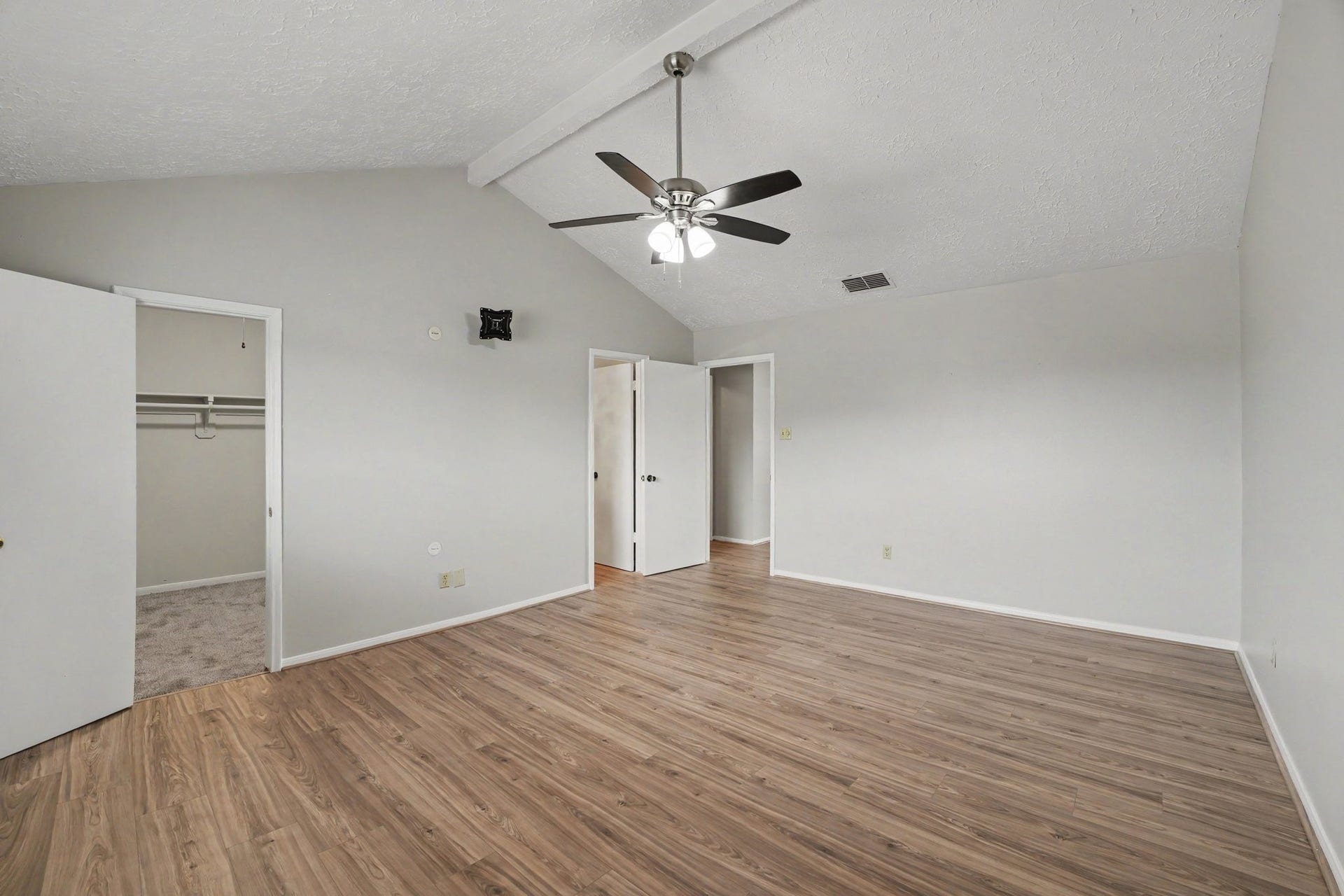 44 Chapparal Court, Missouri City, TX 77459 The spacious primary bedroom retreat features dramatic vaulted ceilings with a prominent central support beam and a stylish ceiling fan with integrated lighting.
