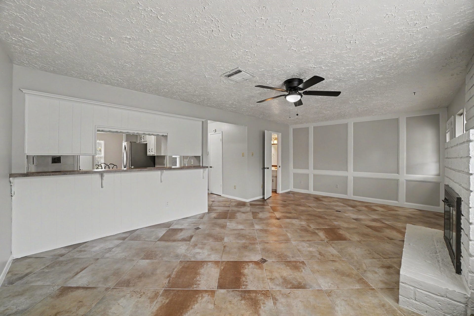 44 Chapparal Court, Missouri City, TX 77459 This expansive main living space highlights architectural elegance with its distinctive floor-to-ceiling accent wall featuring geometric picture-frame molding.