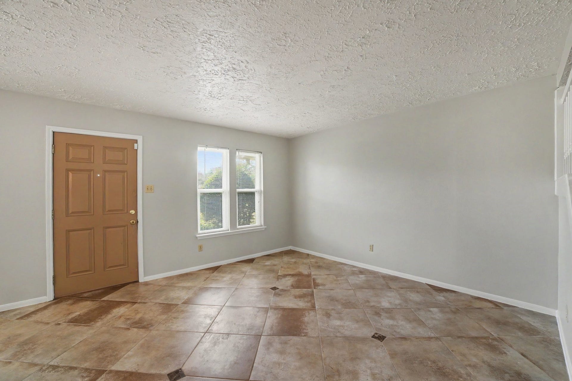 44 Chapparal Court, Missouri City, TX 77459 Inside, the welcoming entryway opens into a light-filled, versatile living space accented by cool gray walls and crisp white trim. Large double windows outfitted with blinds allow plenty of natural sunlight to spill across the expansive, diagonally laid tile flooring, which features subtle, earthy mottling and decorative dark accent corner tiles.