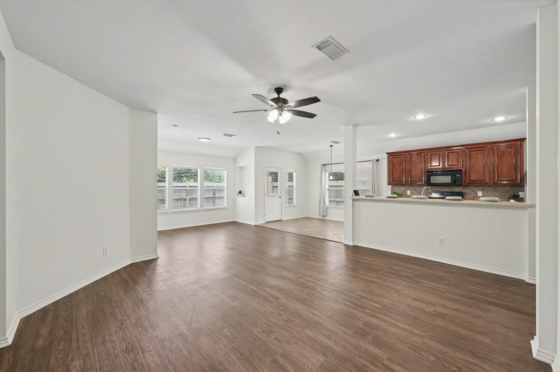 Follow the flooring into the heart of the home, where the living room opens generously toward the kitchen and breakfast area for effortless daily connection.
