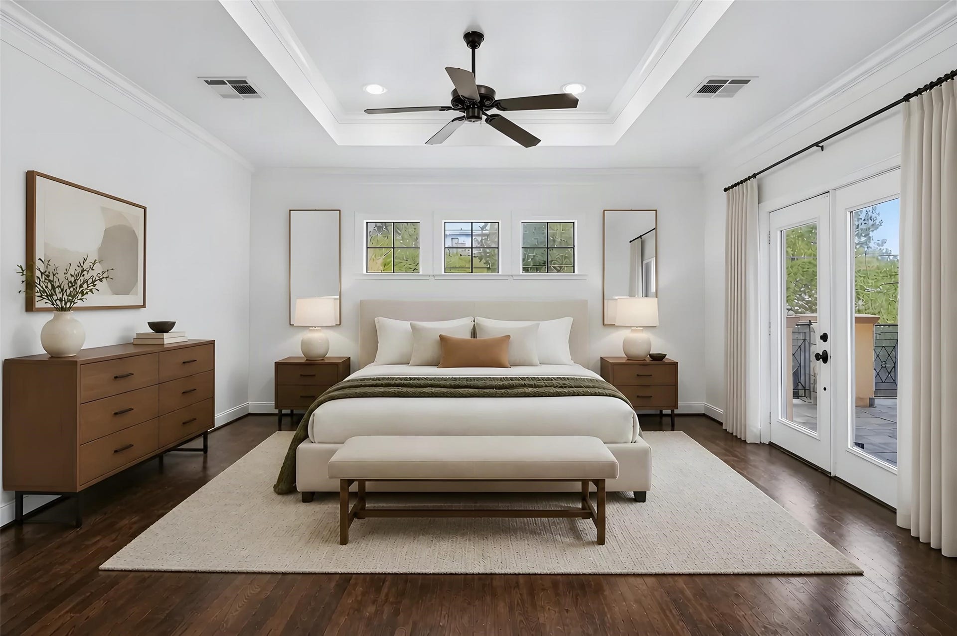 Experience luxury in this spacious bedroom featuring a tray ceiling, elegant hardwood floors, and abundant natural light through French doors leading to a private balcony. *Photo is virtually staged*