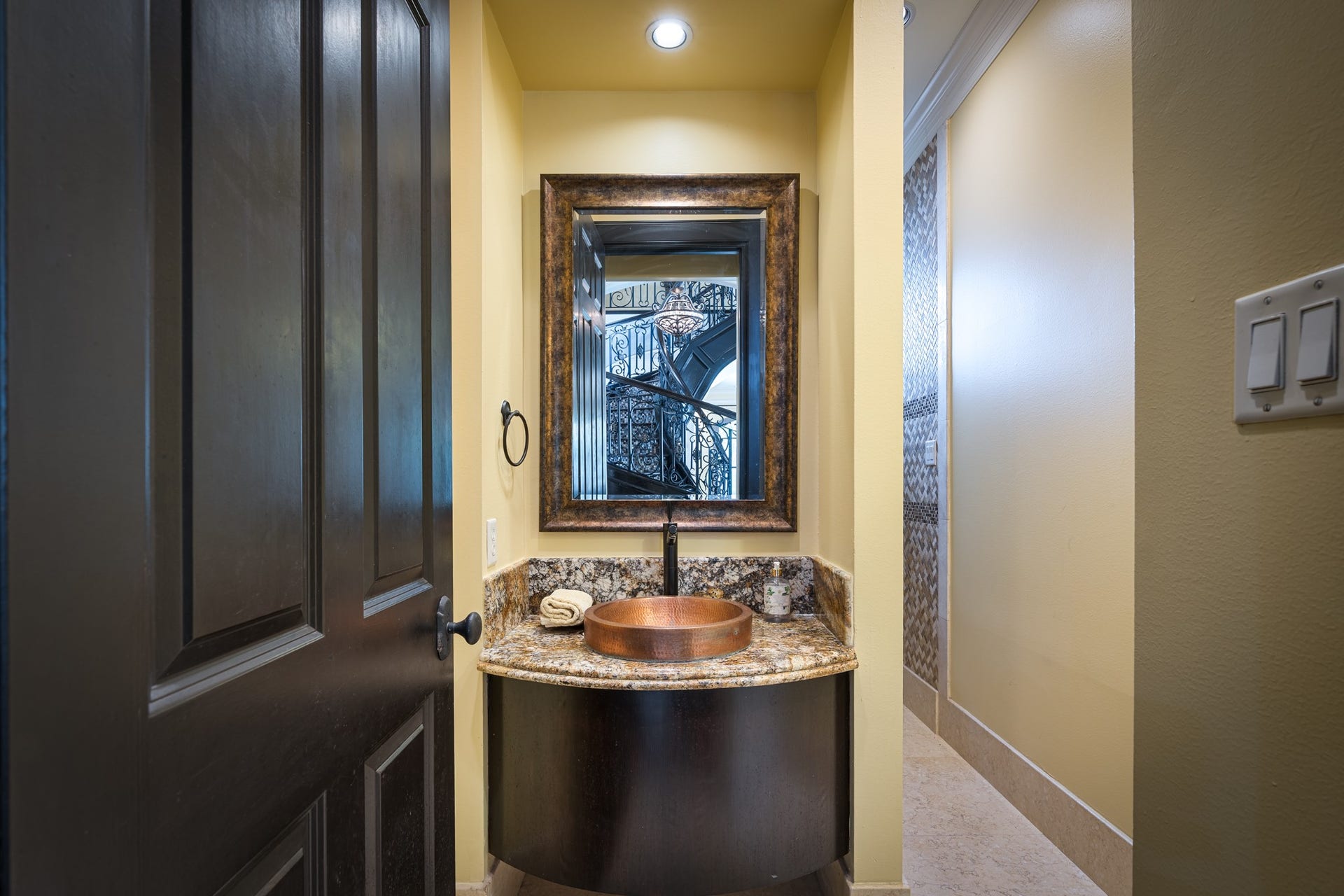 Elegant first-floor full bathroom featuring a granite-topped vanity with a copper vessel sink and walk-in shower.