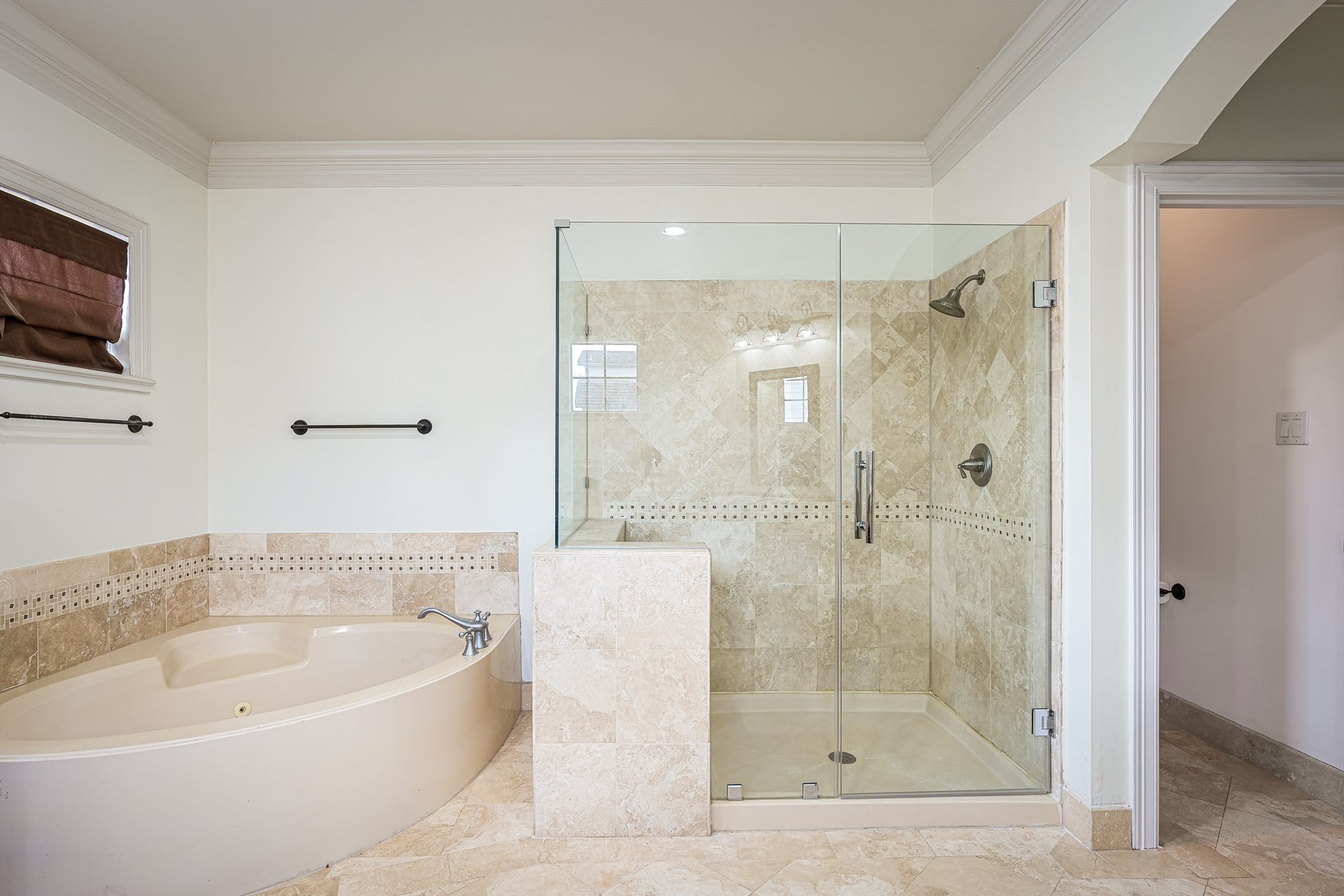 Elegant bathroom featuring a luxurious corner bathtub and a spacious glass-enclosed shower, accented with tasteful tilework for a spa-like retreat.
