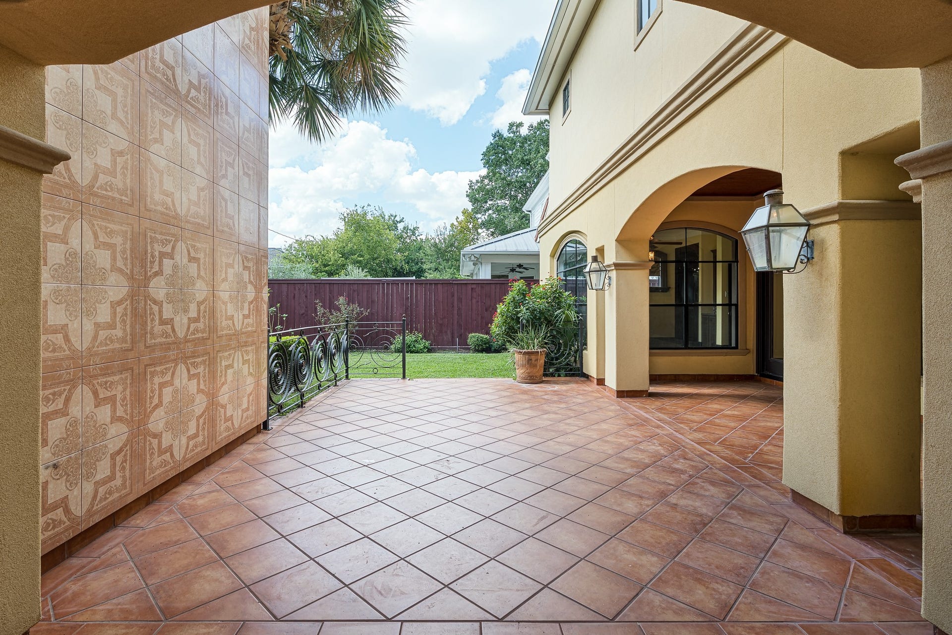 A charming courtyard with elegant tile flooring, decorative wall tiles, and arched entries creates a welcoming outdoor space, perfect for relaxation and entertaining.