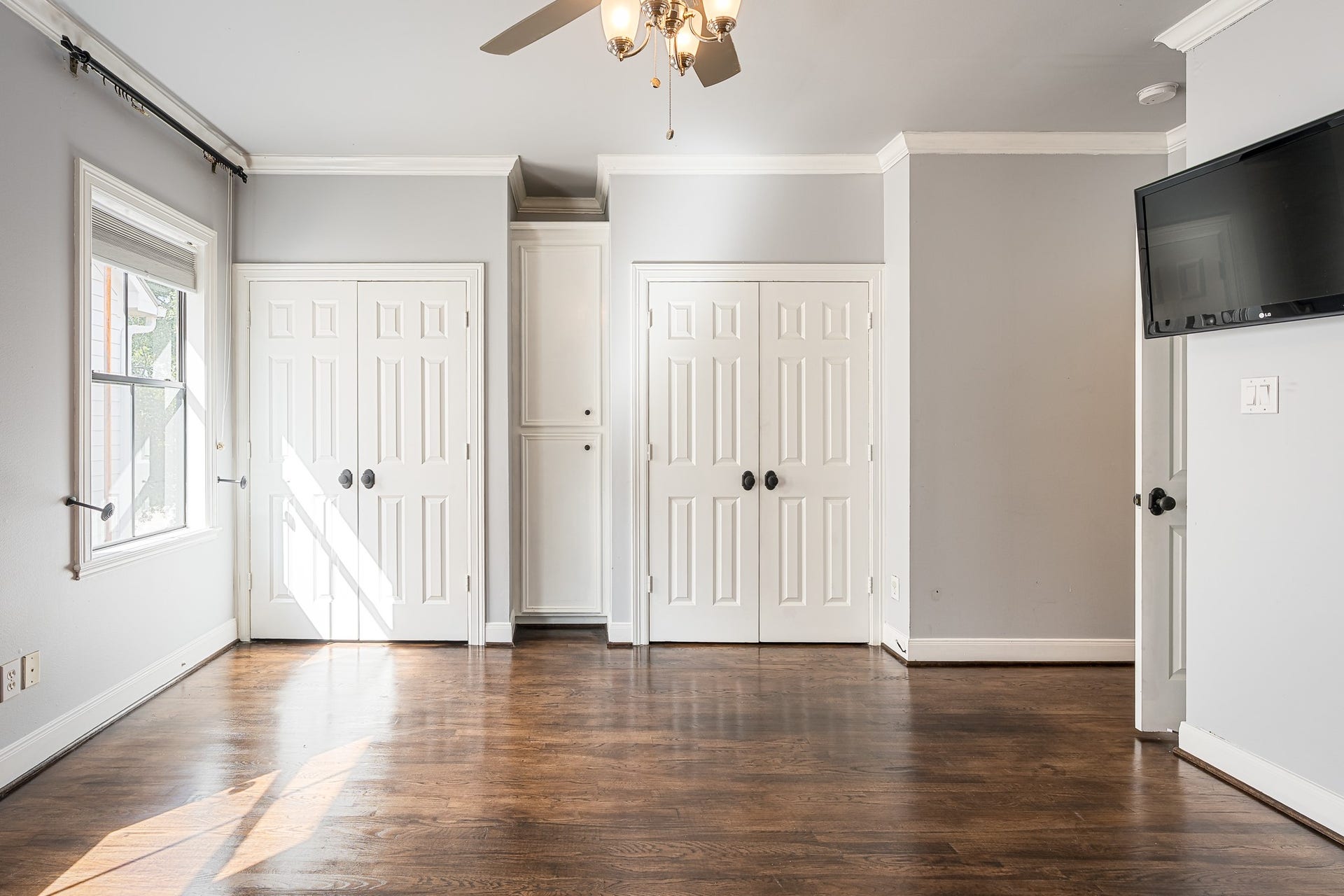 Bright and airy room with rich hardwood floors, dual closets, and a ceiling fan, perfect for a stylish and functional living space.