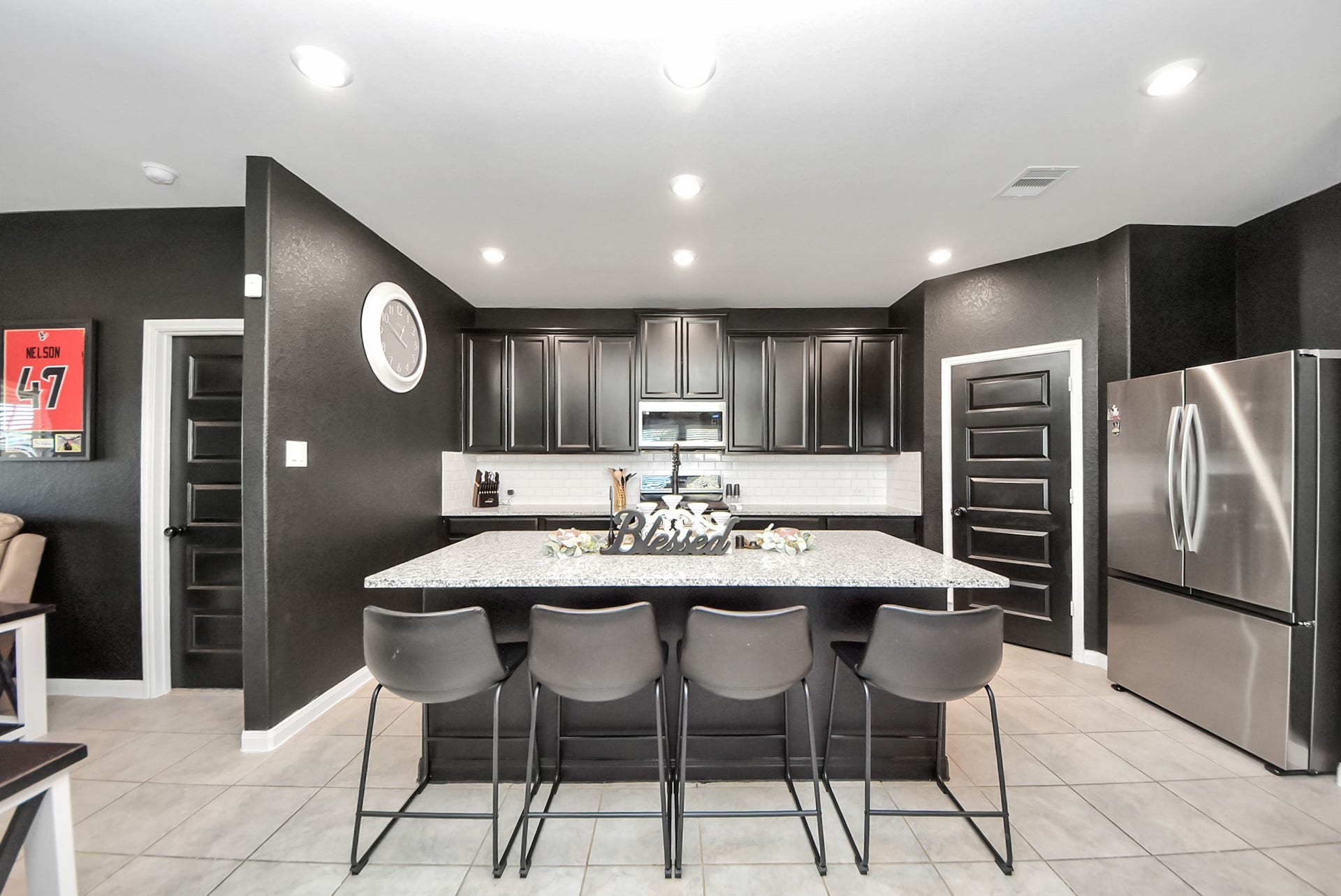 930 Pismo Lane, Rosharon, TX 77583 Modern kitchen with sleek black cabinetry, stainless steel appliances, and a large granite island with seating for four. Bright lighting and tile flooring add to the contemporary feel.