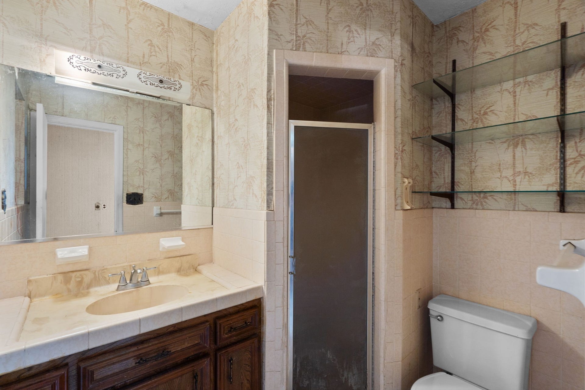 8218 Avenue M, Santa Fe, TX 77510 Bathroom with tiled shower, vanity, and glass shelving.