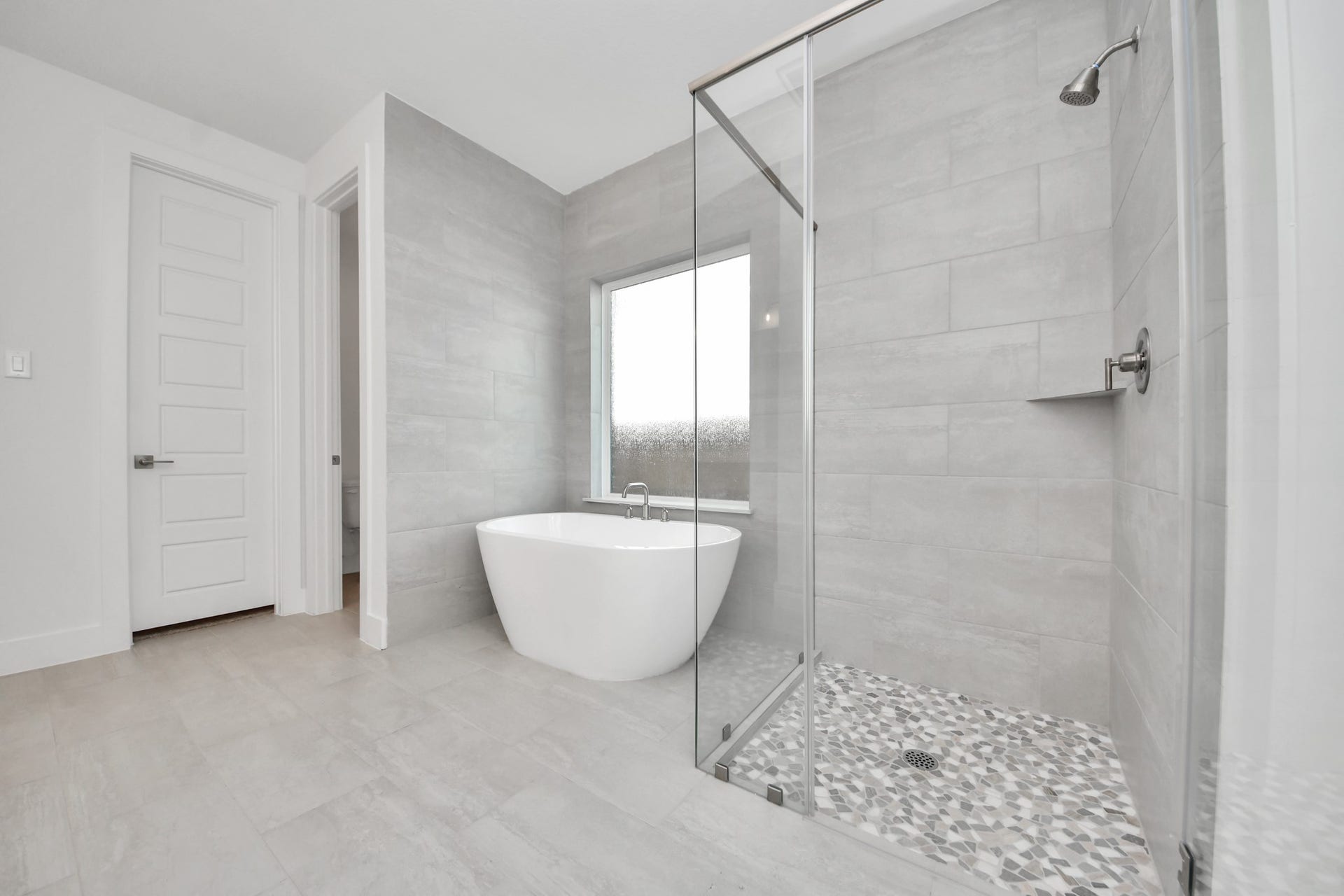 2052 Thimbleberry Lane, Magnolia, TX 77355 Escape to a spa-like oasis in this primary bathroom. Enjoy a walk-in shower with tile surround, a separate garden tub with custom detailing, and an elegant vanity featuring light countertops, modern hardware, and beautiful vanity lights. Experience luxury and relaxation in every detail.