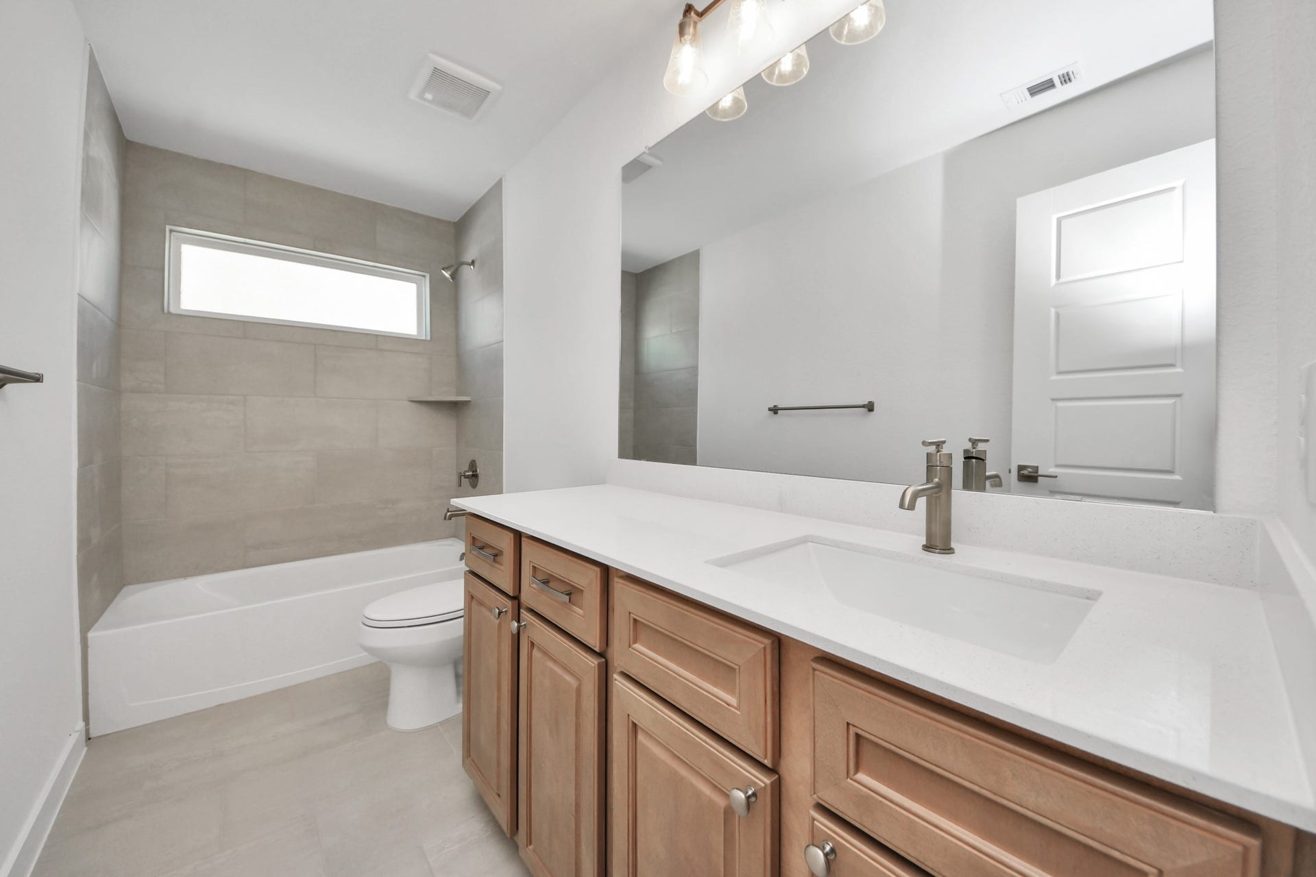 2052 Thimbleberry Lane, Magnolia, TX 77355 Secondary bath features tile flooring, bath/shower combo with tile surround, light stained wood cabinets, beautiful light countertop.