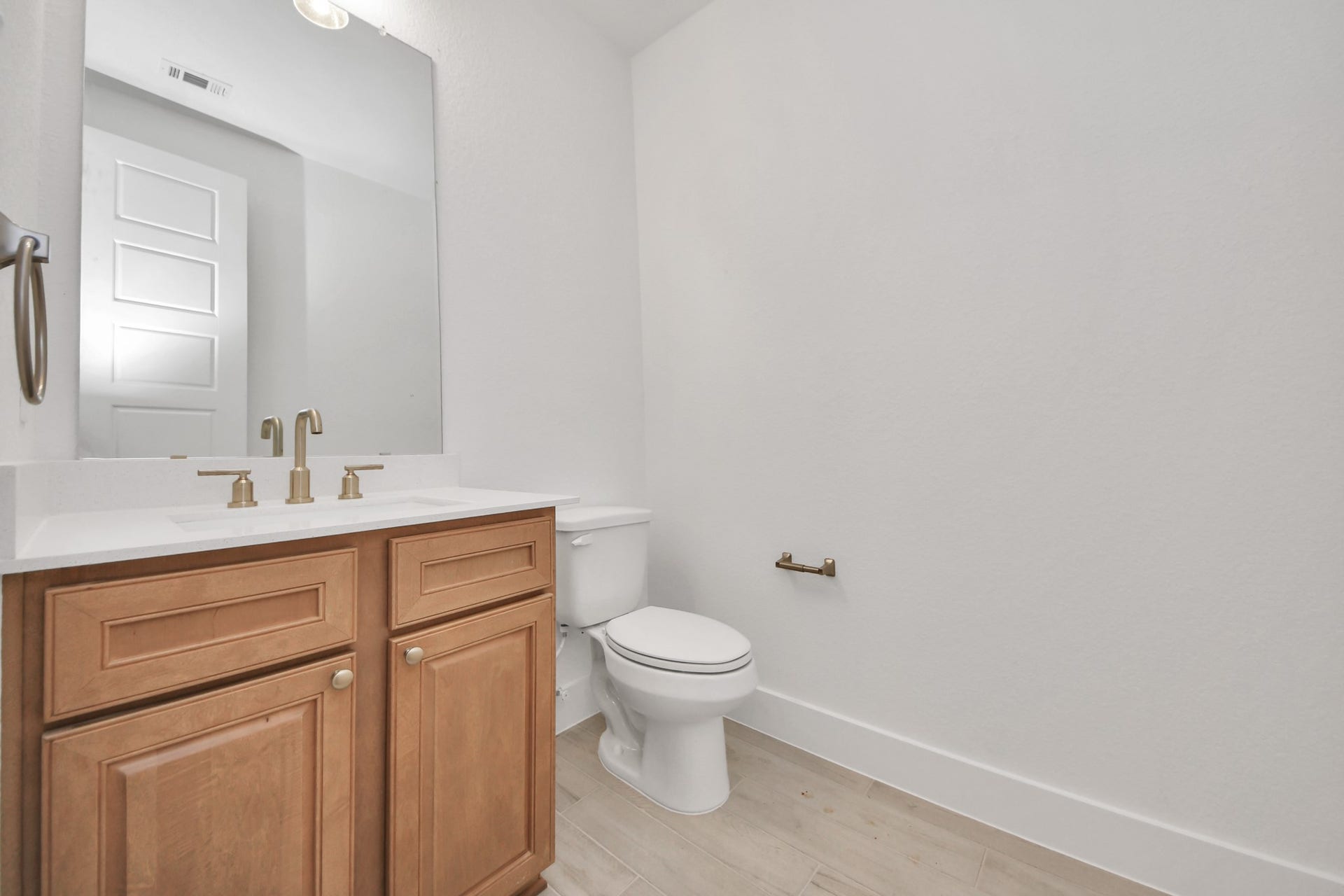 2052 Thimbleberry Lane, Magnolia, TX 77355 Sophisticated half bathroom adorned with contemporary finishes. The elegant 5-panel door welcomes you to a space where style meets functionality. Notice the sleek hardware accents that add a touch of modern charm. The vanity boasts light-colored countertops, beautifully complemented by a tasteful vanity light, creating a well-lit and inviting atmosphere.