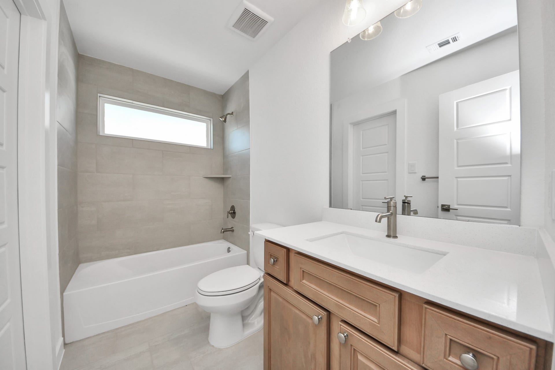 2052 Thimbleberry Lane, Magnolia, TX 77355 Secondary bath features tile flooring, bath/shower combo with tile surround, light stained wood cabinets, beautiful light countertop.