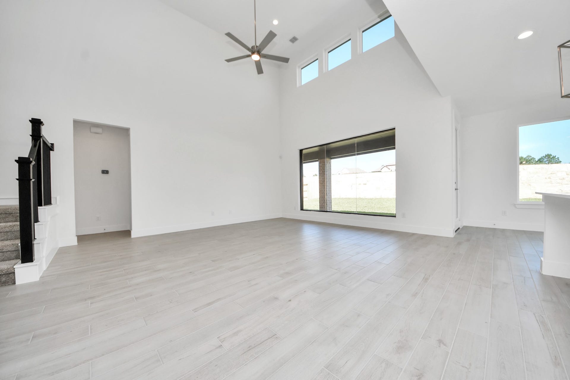 2052 Thimbleberry Lane, Magnolia, TX 77355 Family room flooded with natural light through the expansive windows. The premium tile flooring adds a touch of luxury to the space, creating the perfect setting for relaxing moments and cherished gatherings with loved ones