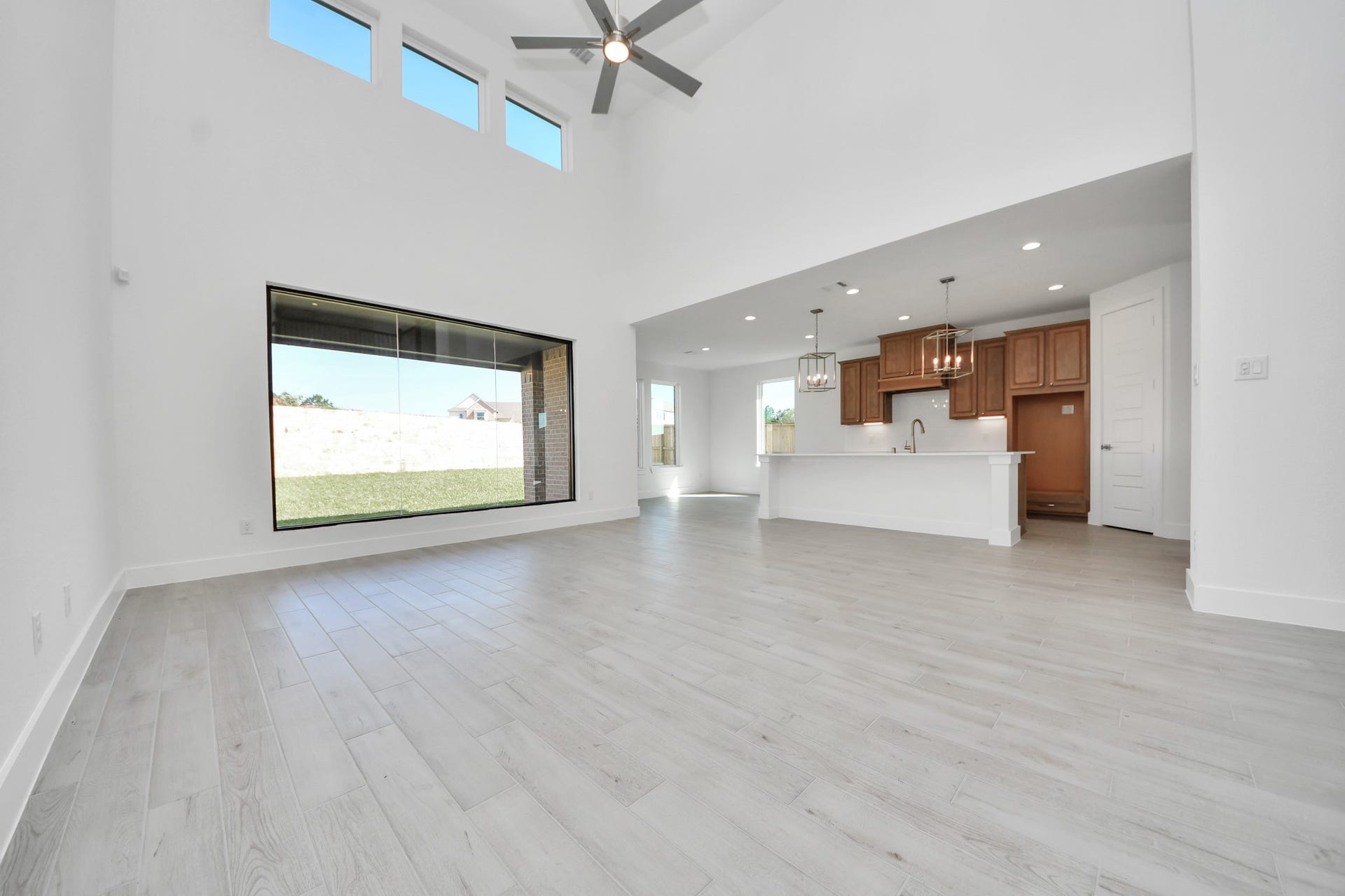 2052 Thimbleberry Lane, Magnolia, TX 77355 Relax and unwind in this inviting family room, illuminated by abundant natural light streaming in through tall windows, complemented by high ceilings and stunning flooring. Stay comfortable year-round with the gentle breeze from the ceiling fan, creating the perfect atmosphere for family gatherings.