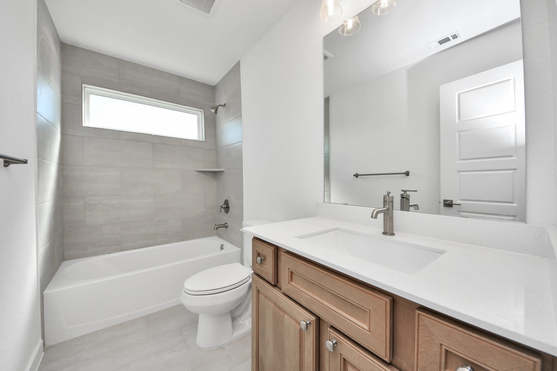 2052 Thimbleberry Lane, Magnolia, TX 77355 Secondary bath features tile flooring, bath/shower combo with tile surround, light stained wood cabinets, beautiful light countertop.