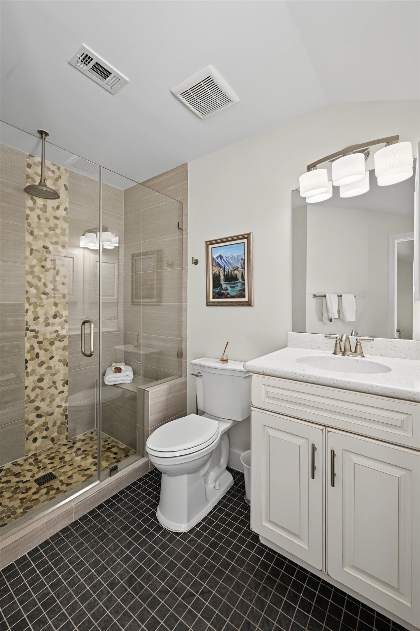 5879 Valley Forge Drive, #107, Houston, TX 77057 The en-suite bath for primary 1 has a sleek glass enclosed shower with bench and rain shower head. A vanity has quartz counters and built-in shelves to the right of the photo.