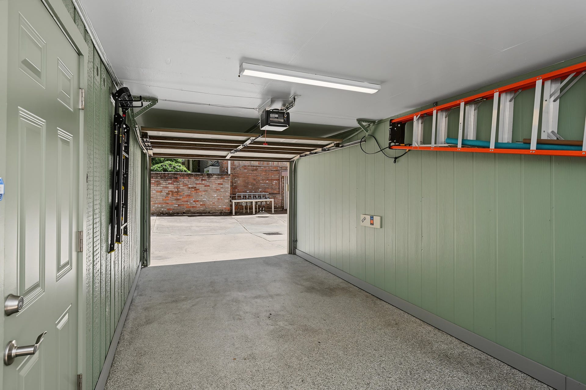 5879 Valley Forge Drive, #107, Houston, TX 77057 The carport is almost fully enclosed and has updated paint, lighting, and epoxy floors. Door to the left leads into the garage.