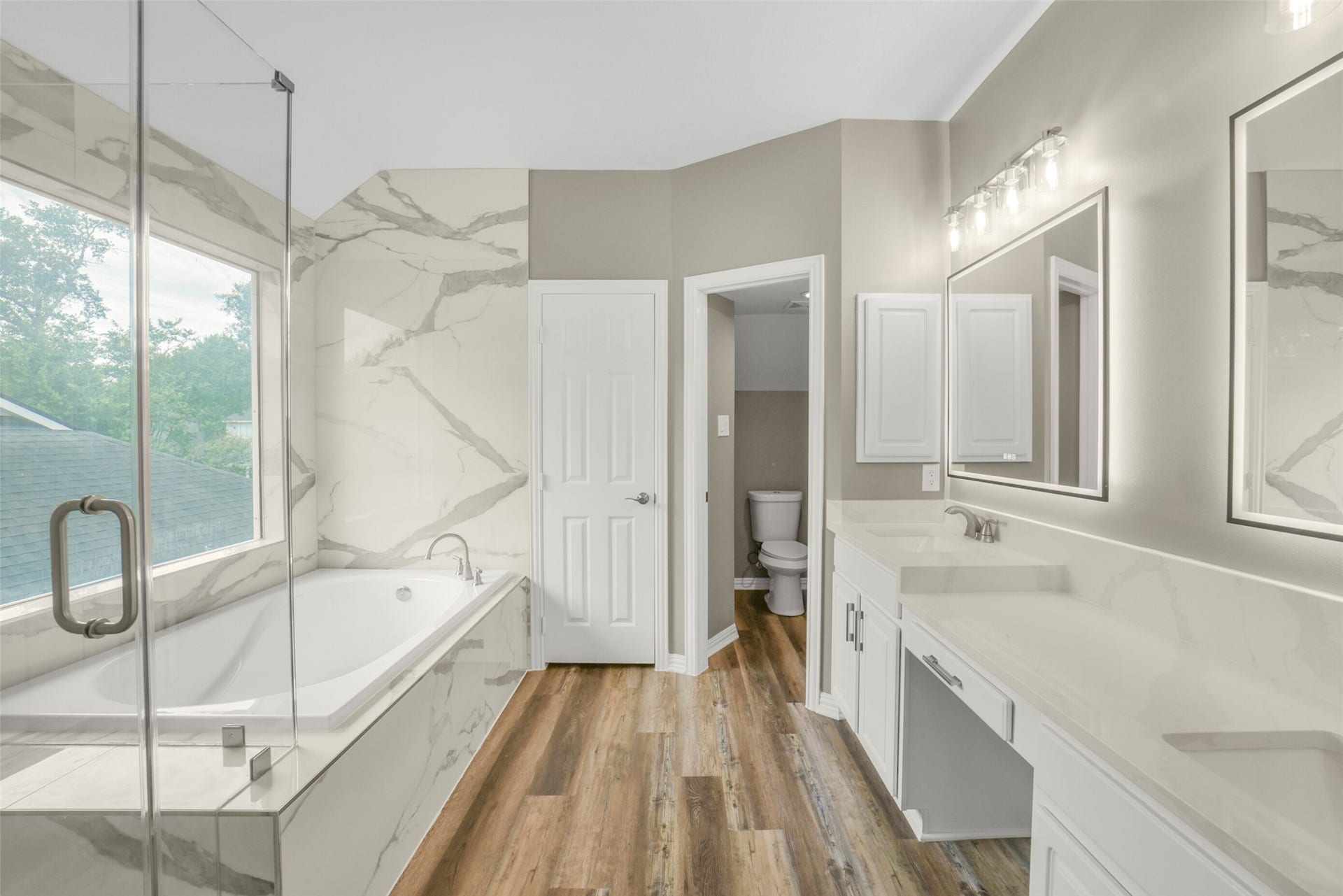 13023 Norstrum Falls Court, Cypress, TX 77429 The spa-like primary bath features dual sinks with a vanity, a deep soaking tub, a glass enclosed walk-in shower, and a private commode area.