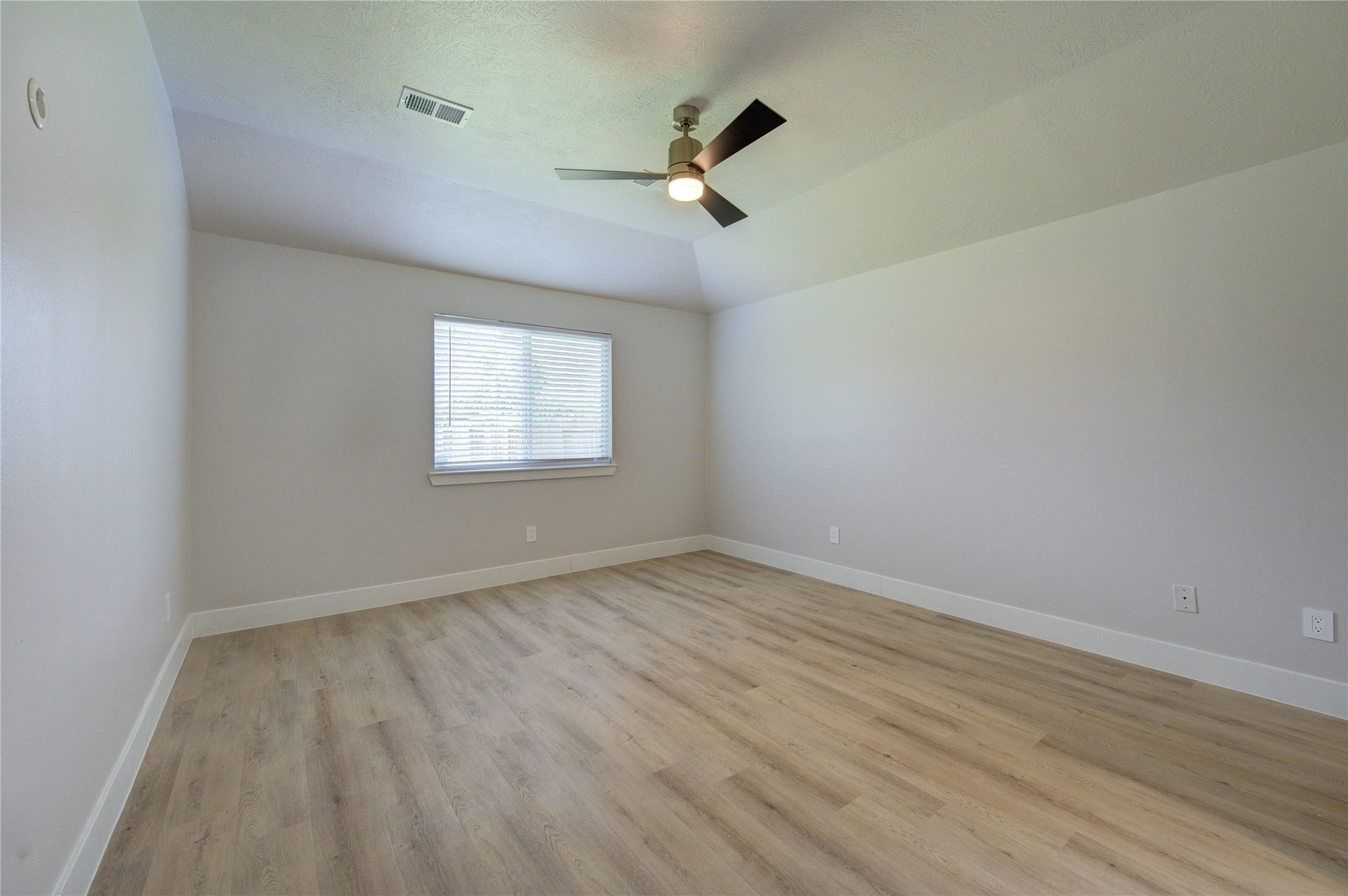 4931 Lake Catherine Court, Richmond, TX 77407 The spacious primary bedroom features a vaulted ceiling, modern ceiling fan, updated wood-look flooring and a large window to fill the room with natural light