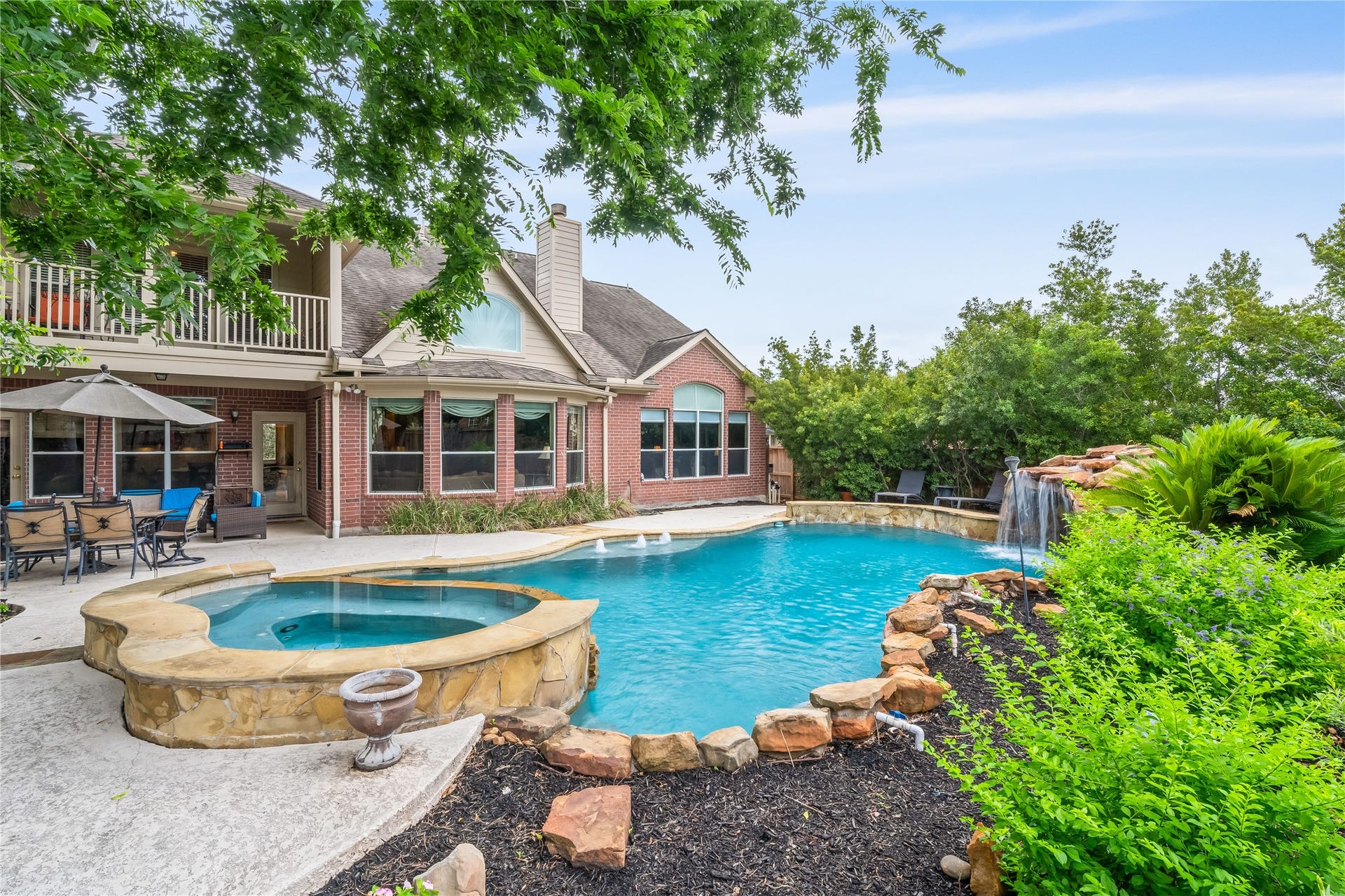 7914 Chianti Court, Sugar Land, TX 77479 Resort-style backyard features a sparkling pool with attached spa, surrounded by lush landscaping and mature trees for added privacy and ambiance.