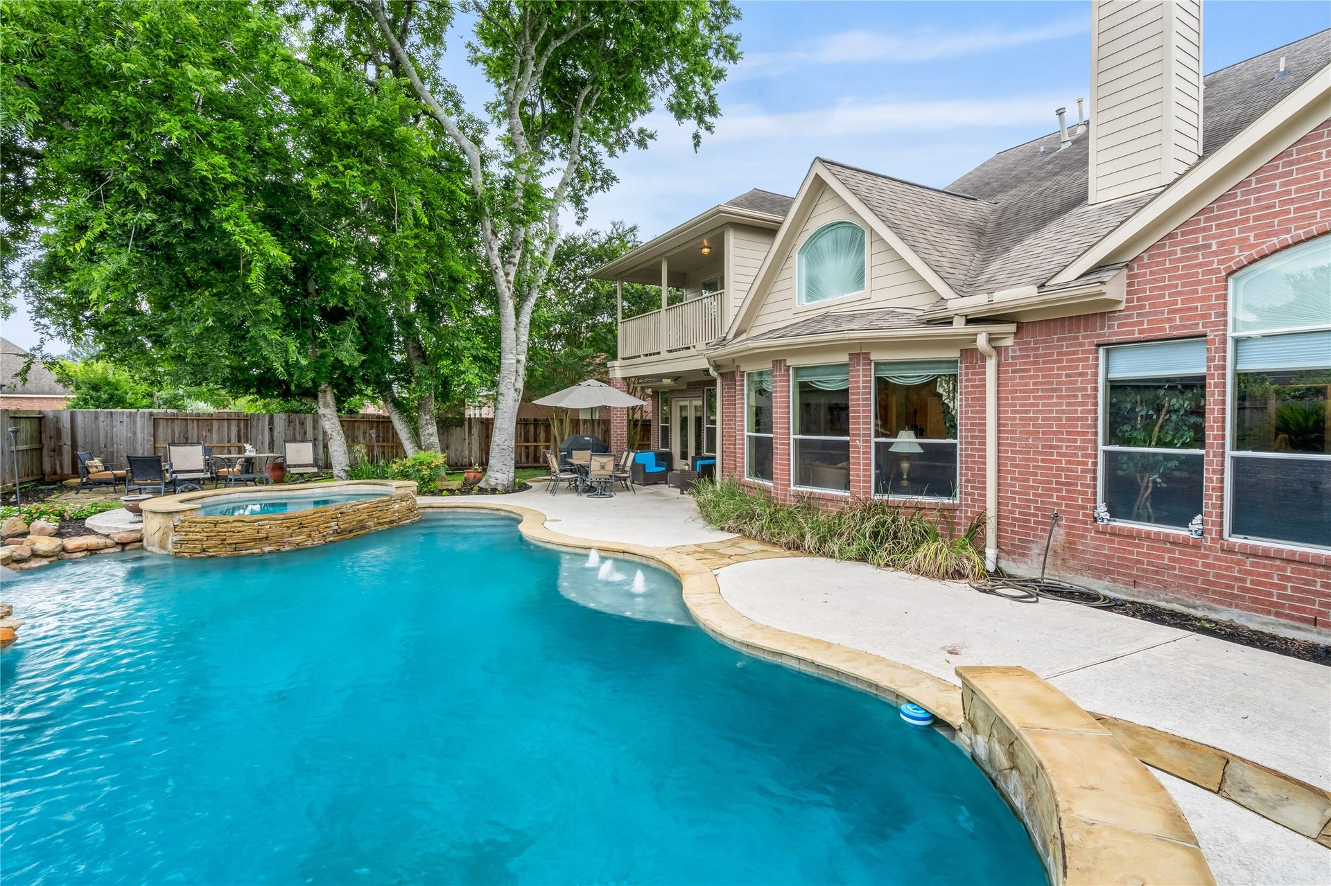 7914 Chianti Court, Sugar Land, TX 77479 Resort-style backyard features a sparkling pool with attached spa, surrounded by lush landscaping and mature trees for added privacy and ambiance.