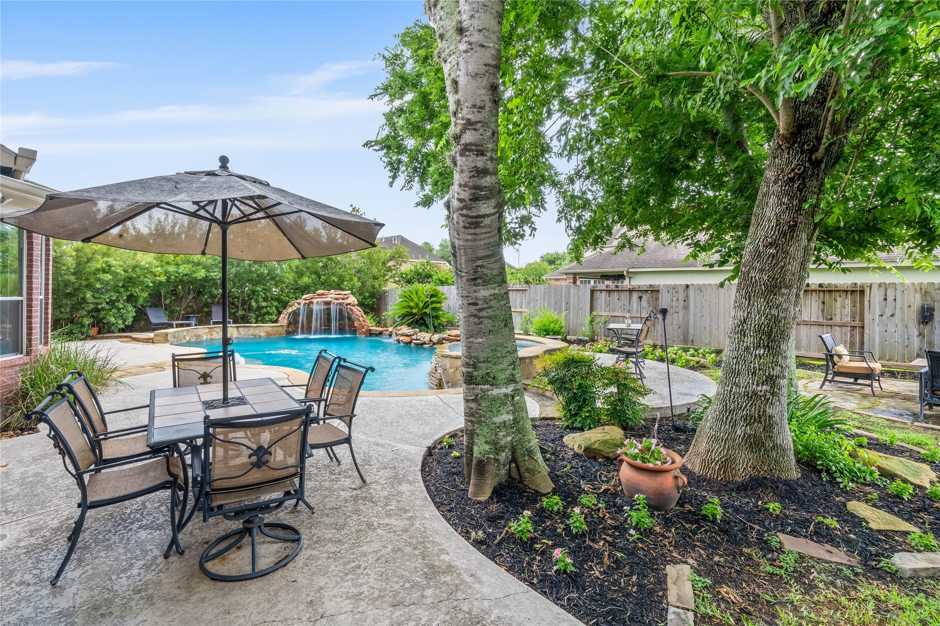 7914 Chianti Court, Sugar Land, TX 77479 Beautifully landscaped yard with mature trees, garden beds, and a spacious patio area enhances the outdoor experience around the pool.