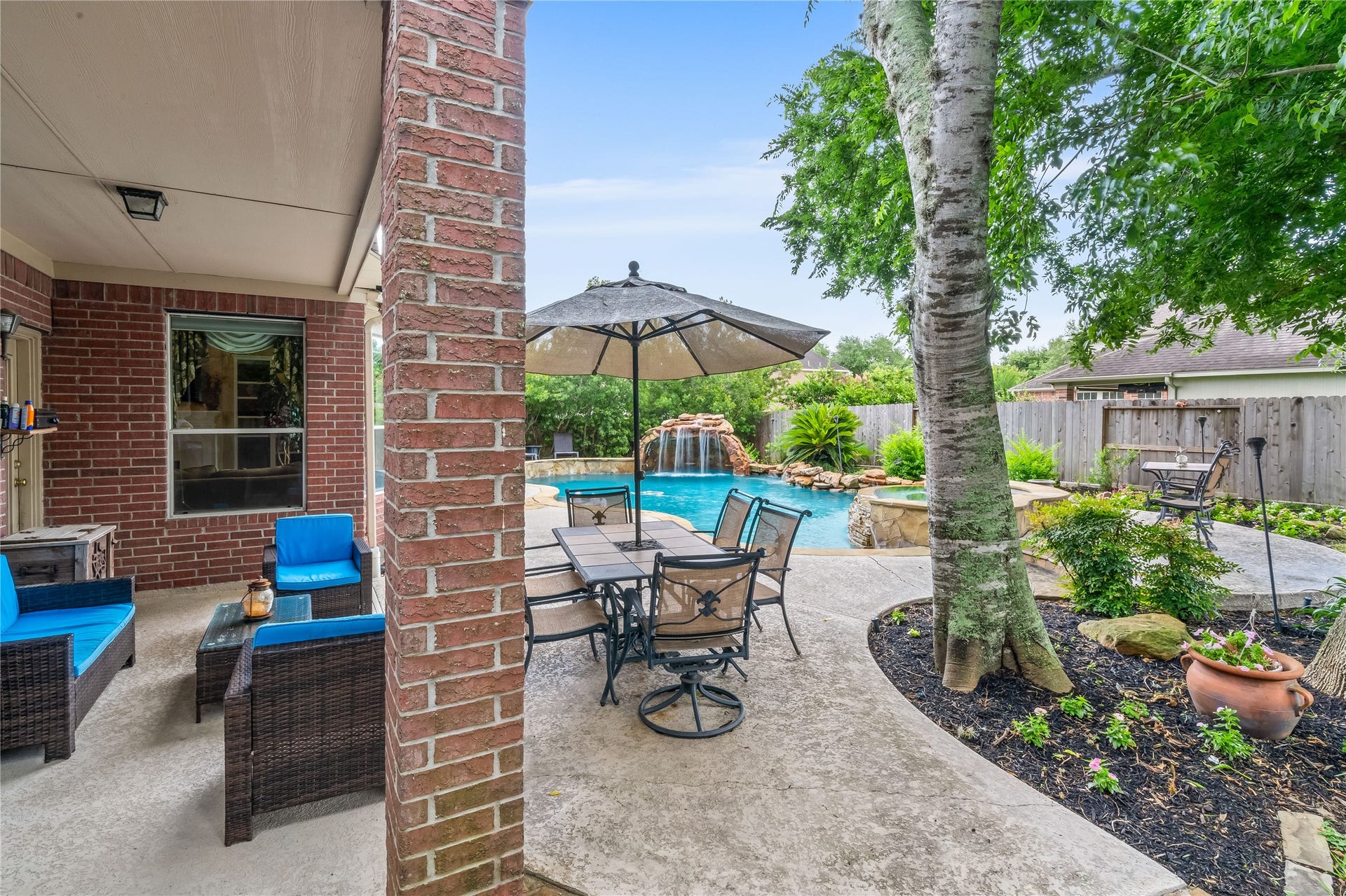 7914 Chianti Court, Sugar Land, TX 77479 Covered patio overlooks the pool and waterfall feature, with multiple seating areas perfect for hosting gatherings or enjoying quiet evenings outdoors.