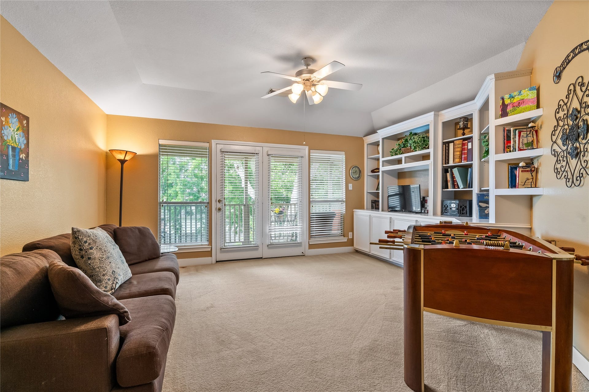 7914 Chianti Court, Sugar Land, TX 77479 Spacious game room features built-in shelving, ceiling fan, and French doors leading to a private balcony, perfect for recreation or relaxation.