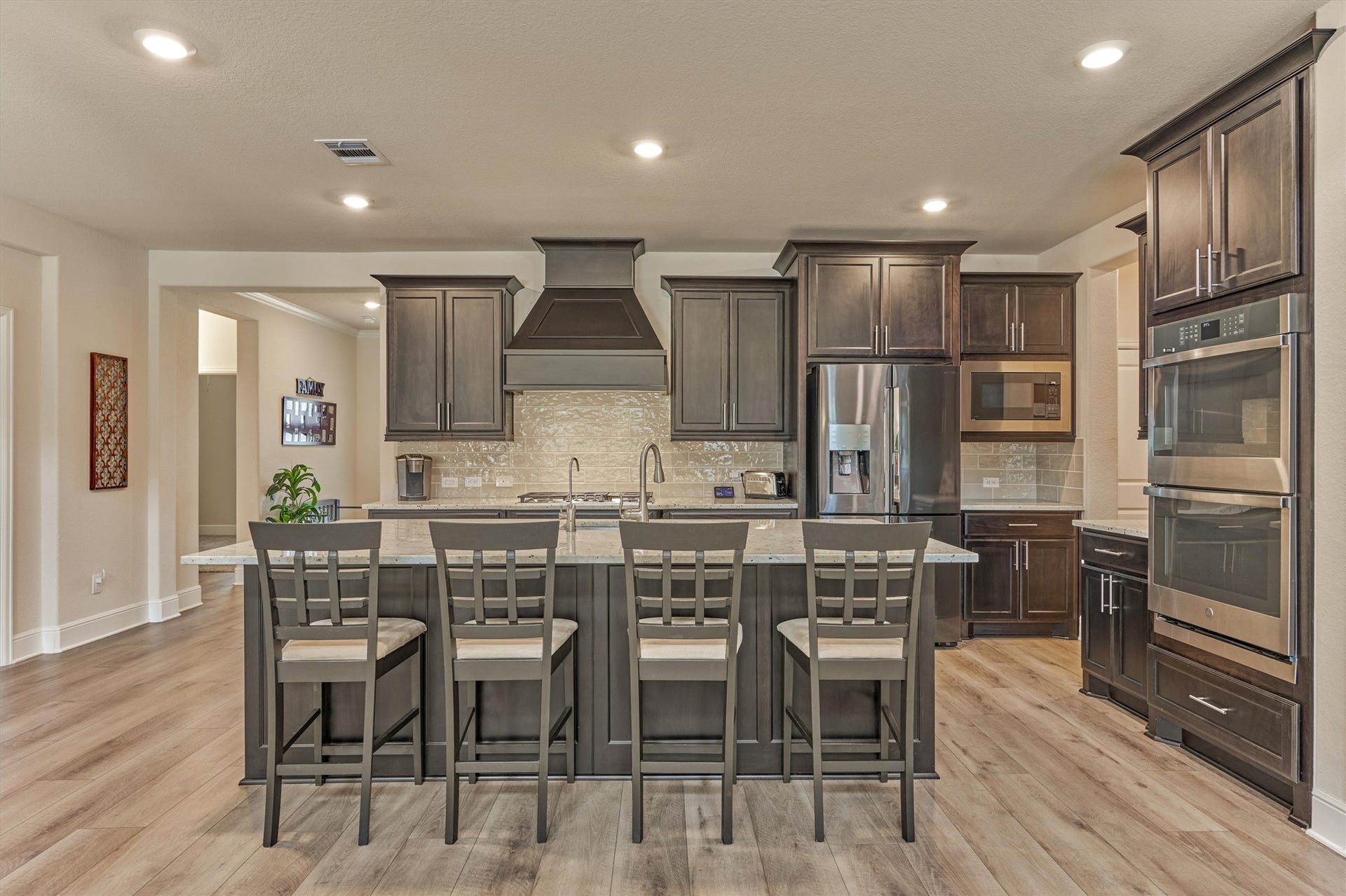 The kitchen has beautifully stained cabinetry, seating for four at the island, double ovens, and a large vent hood.
