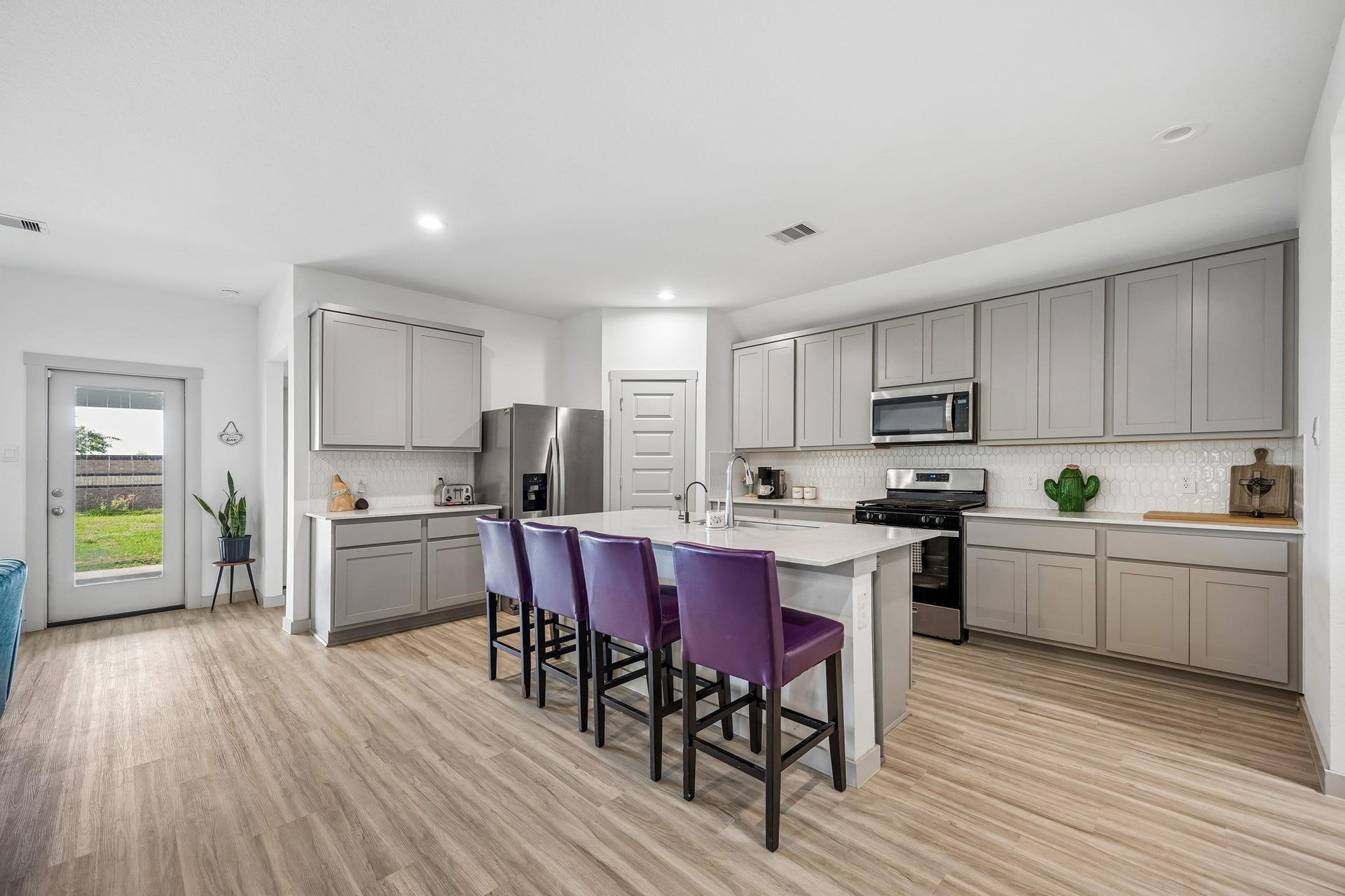 3938 Hordley Terrace Trail, Fulshear, TX 77441 Open kitchen with quartz countertops, a gas range, walk-in pantry, and a large island with seating overlooking the adjoining living and dining areas.