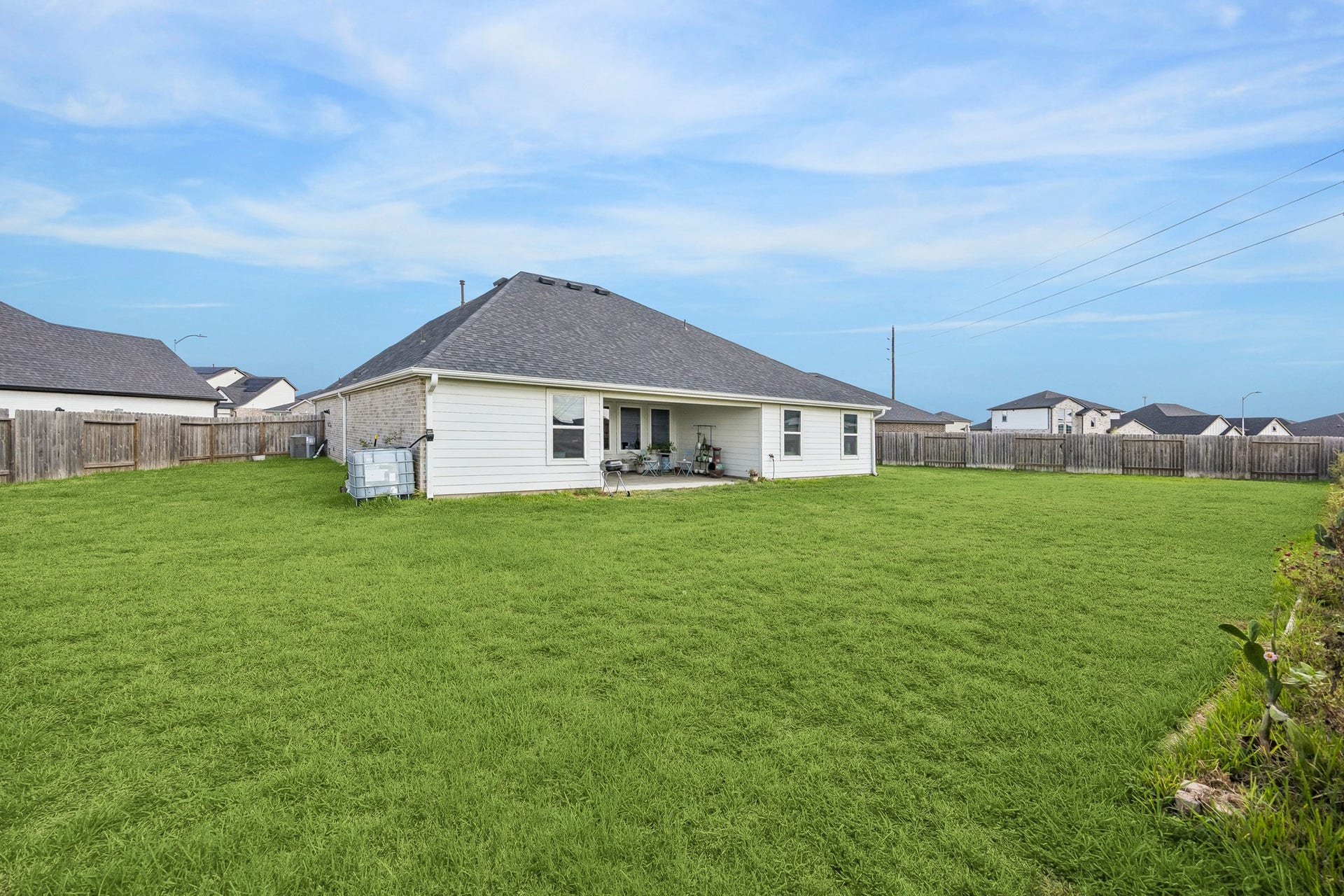 3938 Hordley Terrace Trail, Fulshear, TX 77441 A second look at the backyard highlights the expansive green space and large covered patio, offering plenty of room to relax, play, or entertain outdoors.