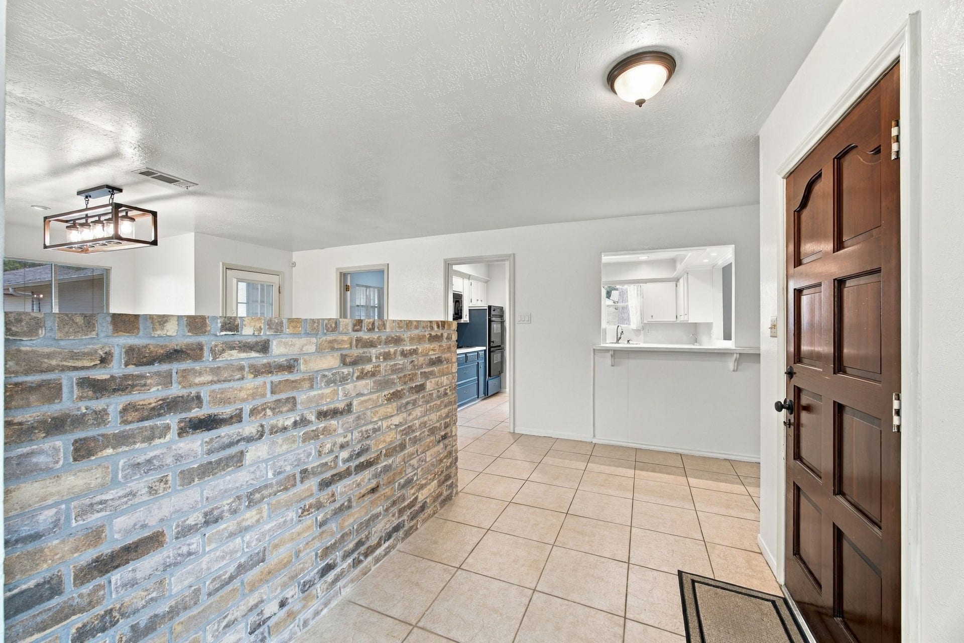 8902 Rocky Lane, Houston, TX 77040 Guests are greeting into this foyer with a brick entrance. The dining room is on the other side of the wall.