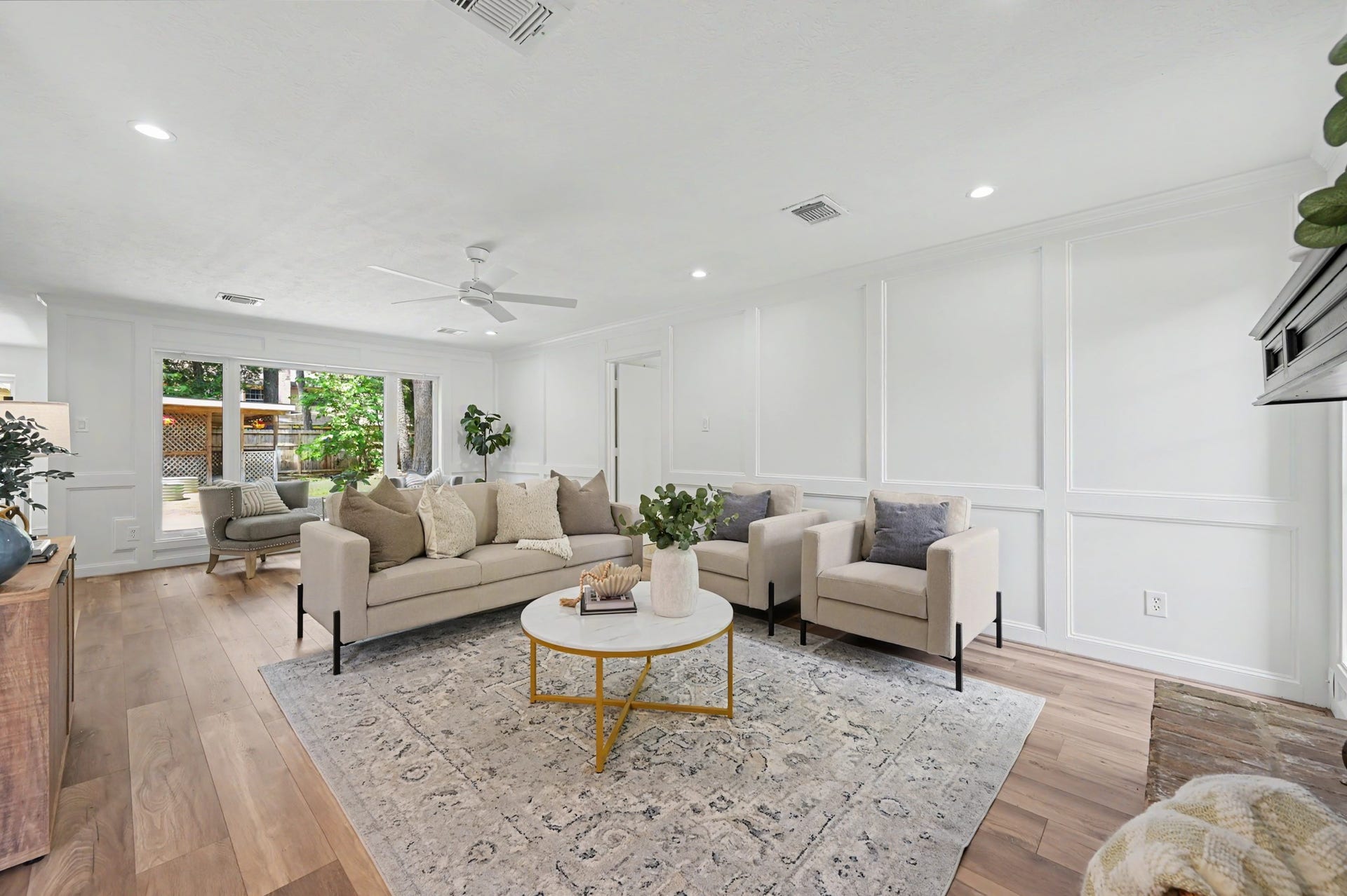 19 Postvine Court, The Woodlands, TX 77381 Bright open-concept living area featuring luxury vinyl flooring, elegant wainscoting, & picture window overlooking the patio, gazebo & large backyard.