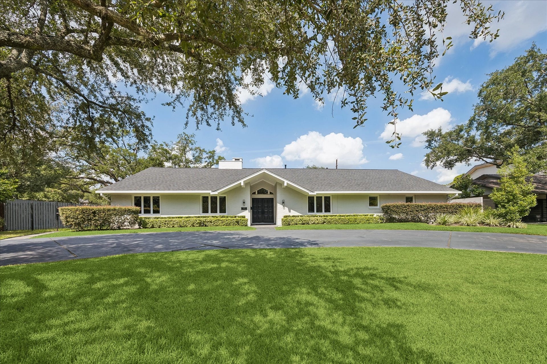 Beautifully appointed single-story home with a welcoming front entrance and situated on a professionally landscaped lot with mature trees and a circular driveway.