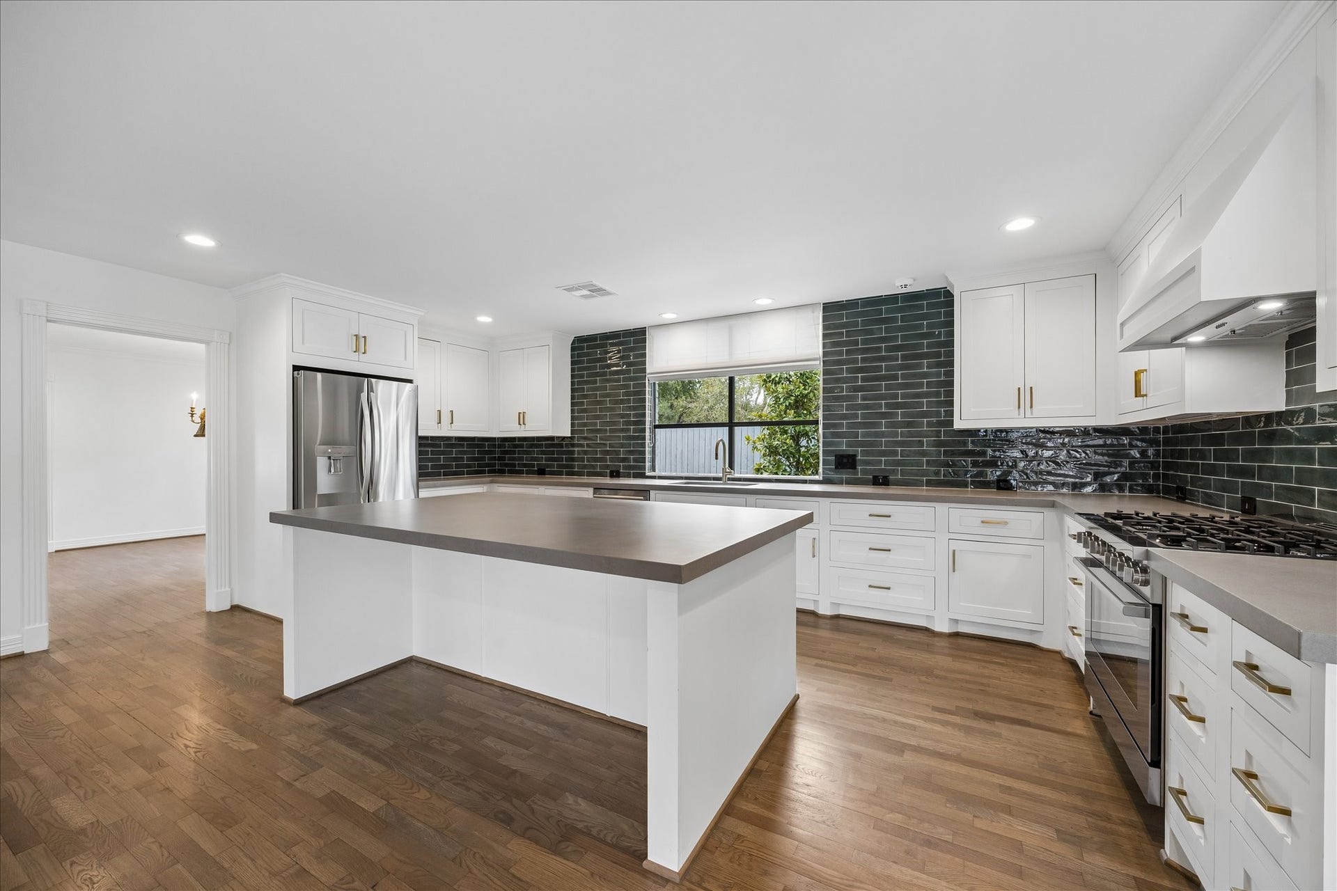 The tastefully updated kitchen pairs crisp white cabinetry and brass hardware with striking designer green subway tile for a sophisticated pop of color.