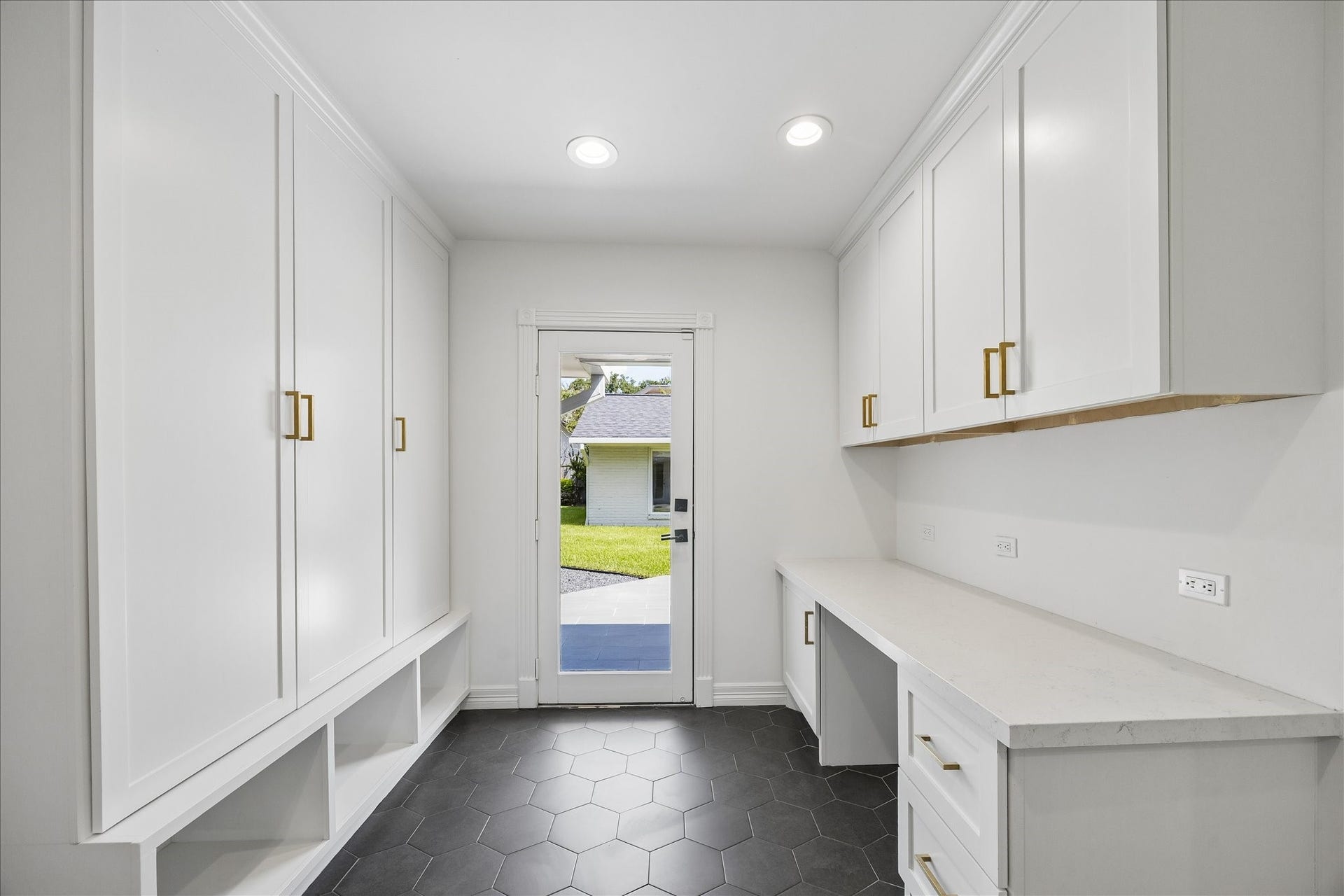 Conveniently located off the garage, the mudroom features built-in lockers, a quartz-topped desk, hexagon tile flooring and direct access to the backyard.