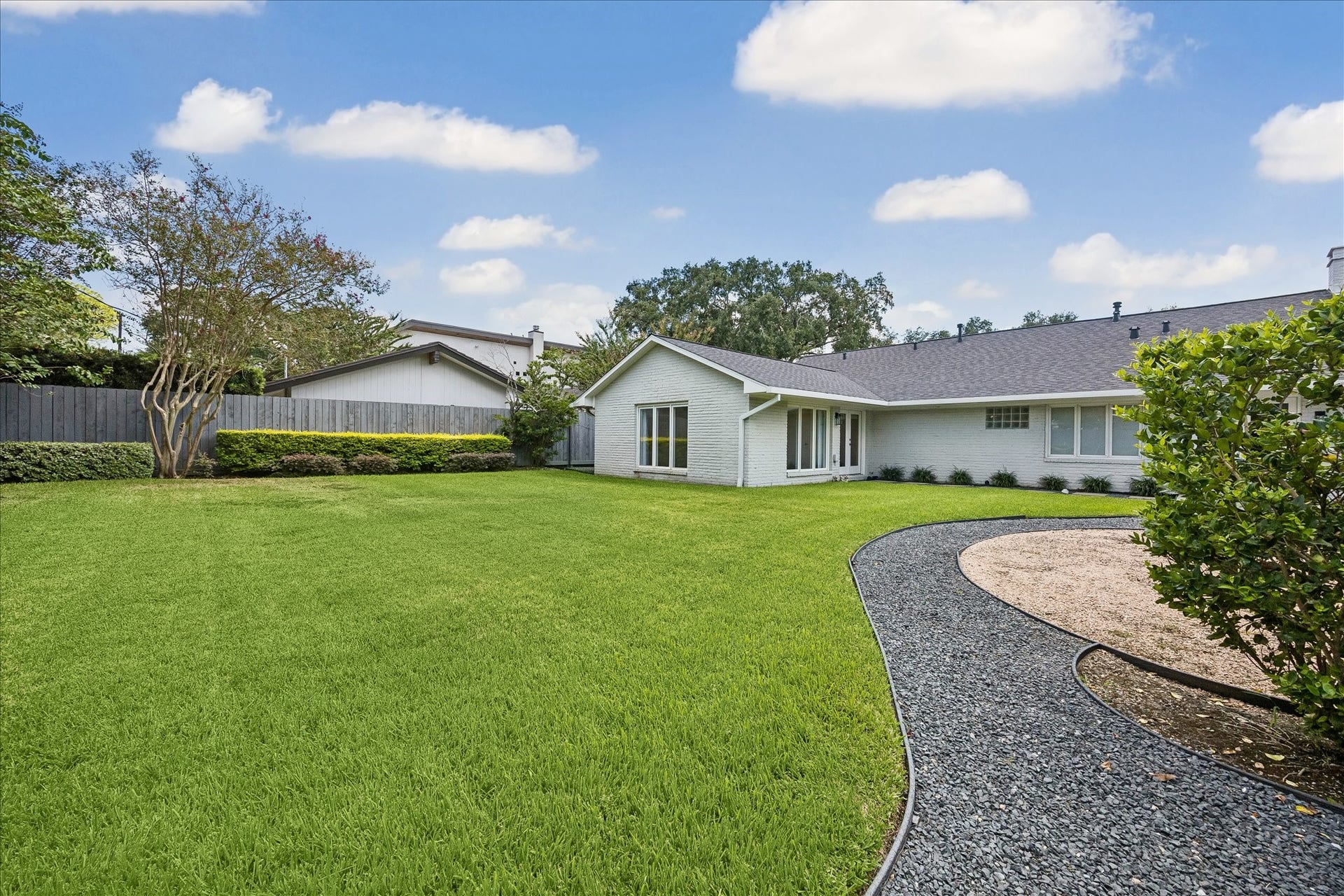 The expansive backyard offers beautifully maintained green space, mature landscaping and ample room for a future pool.