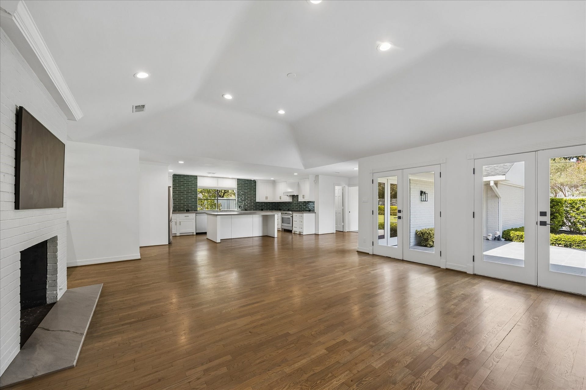 Light-filled family room features a vaulted ceiling, gas-log fireplace, French doors overlooking the backyard and an open flow to the kitchen.