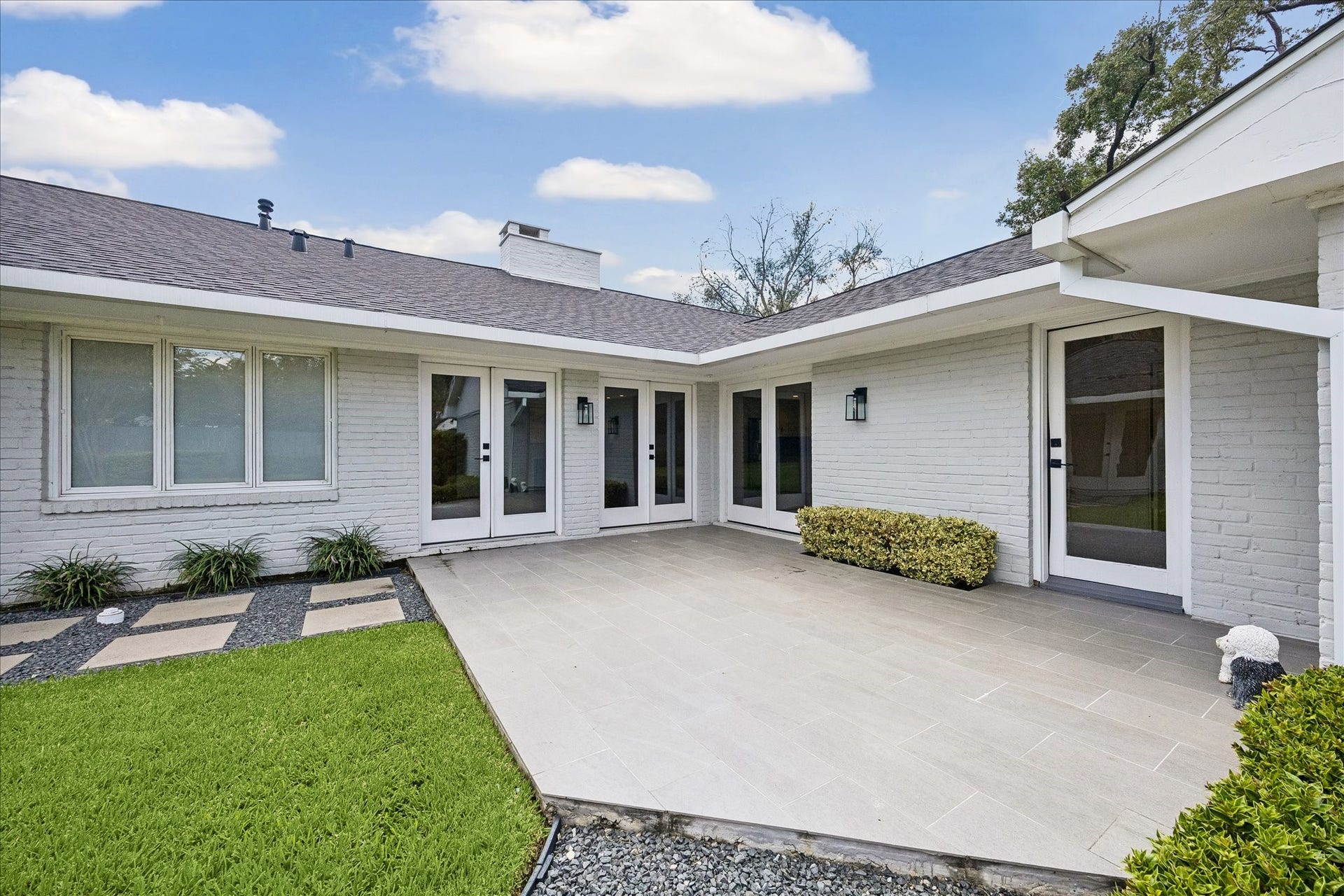 A welcoming backyard patio is surrounded by manicured landscaping and attractive French doors.